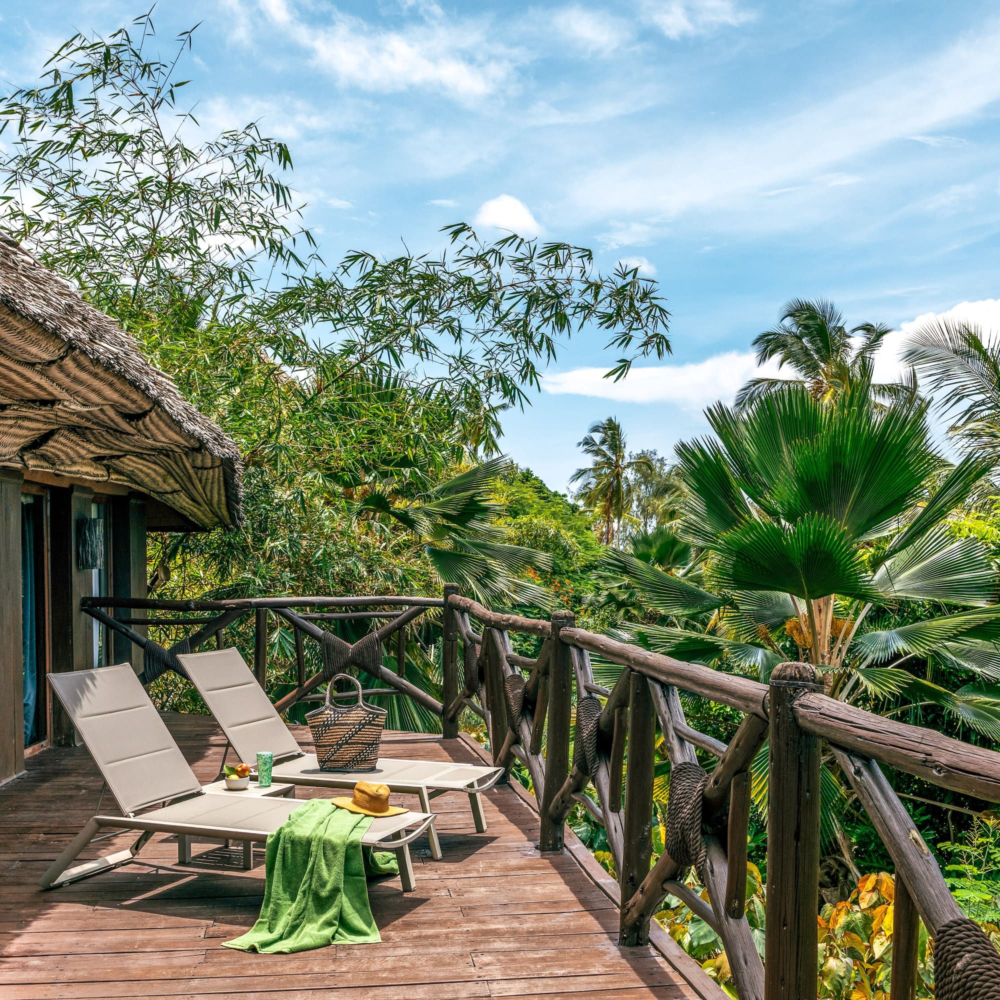 Tropical resort balcony with lounge chairs and lush palm views.