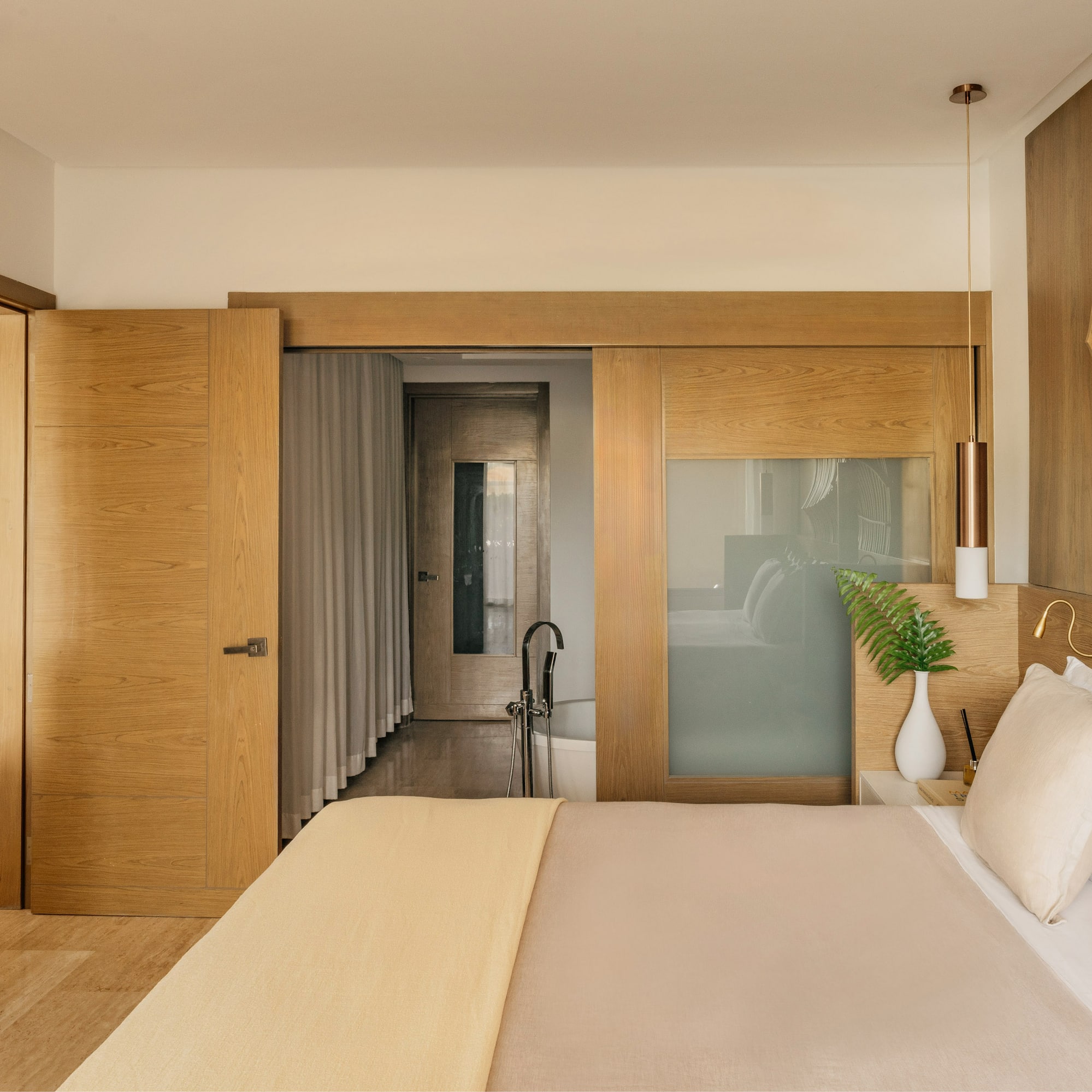Modern bedroom with wooden headboard, sliding doors, and en-suite bathroom.