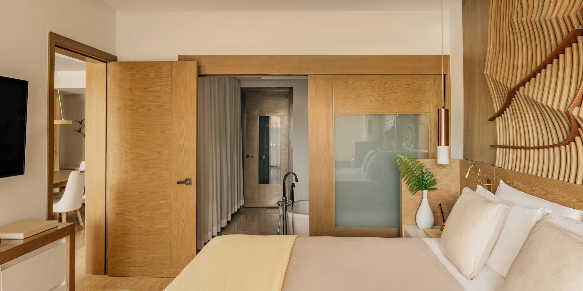 Modern bedroom with wooden headboard, sliding doors, and en-suite bathroom.