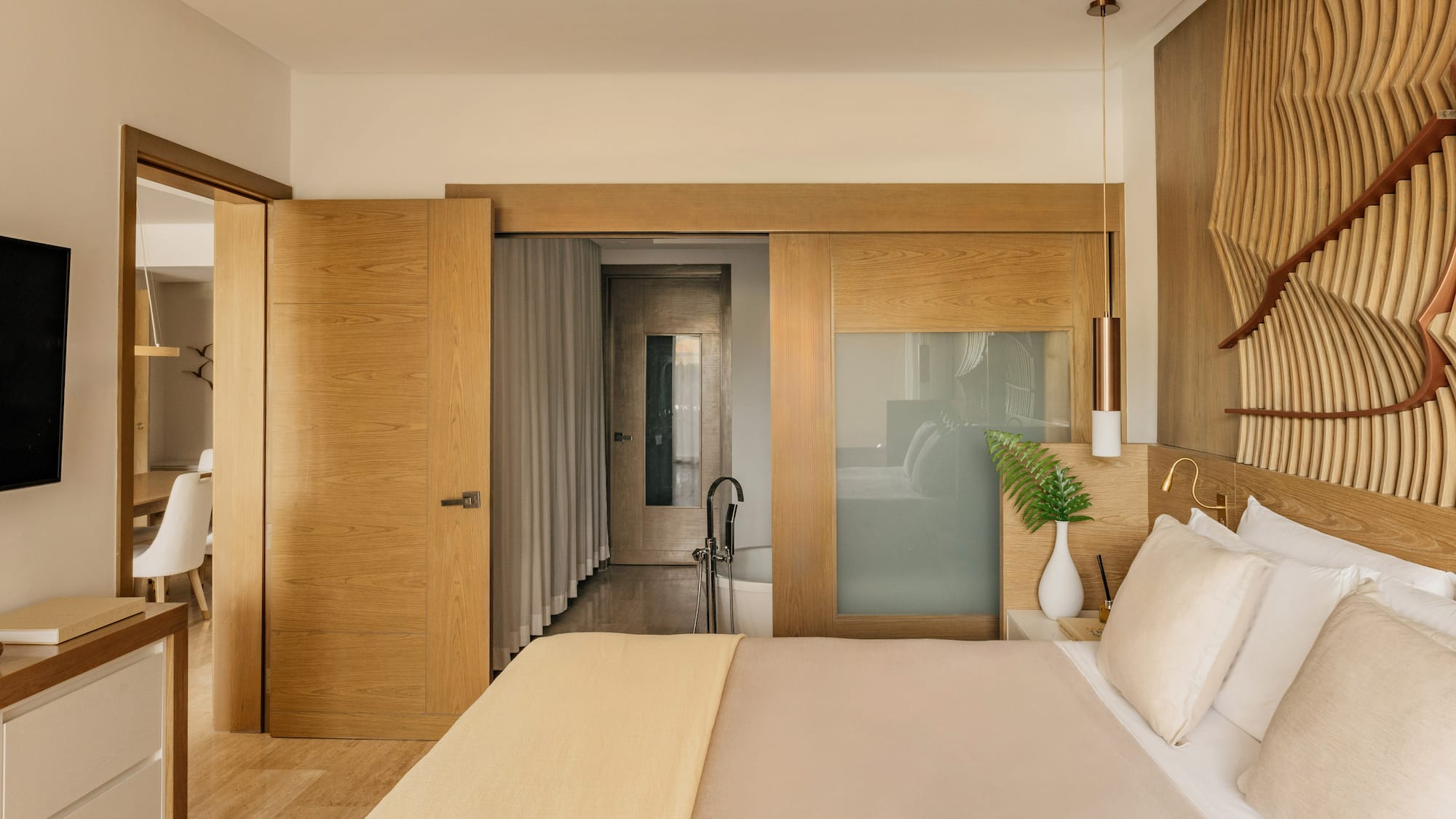 Modern bedroom with wooden headboard, sliding doors, and en-suite bathroom.