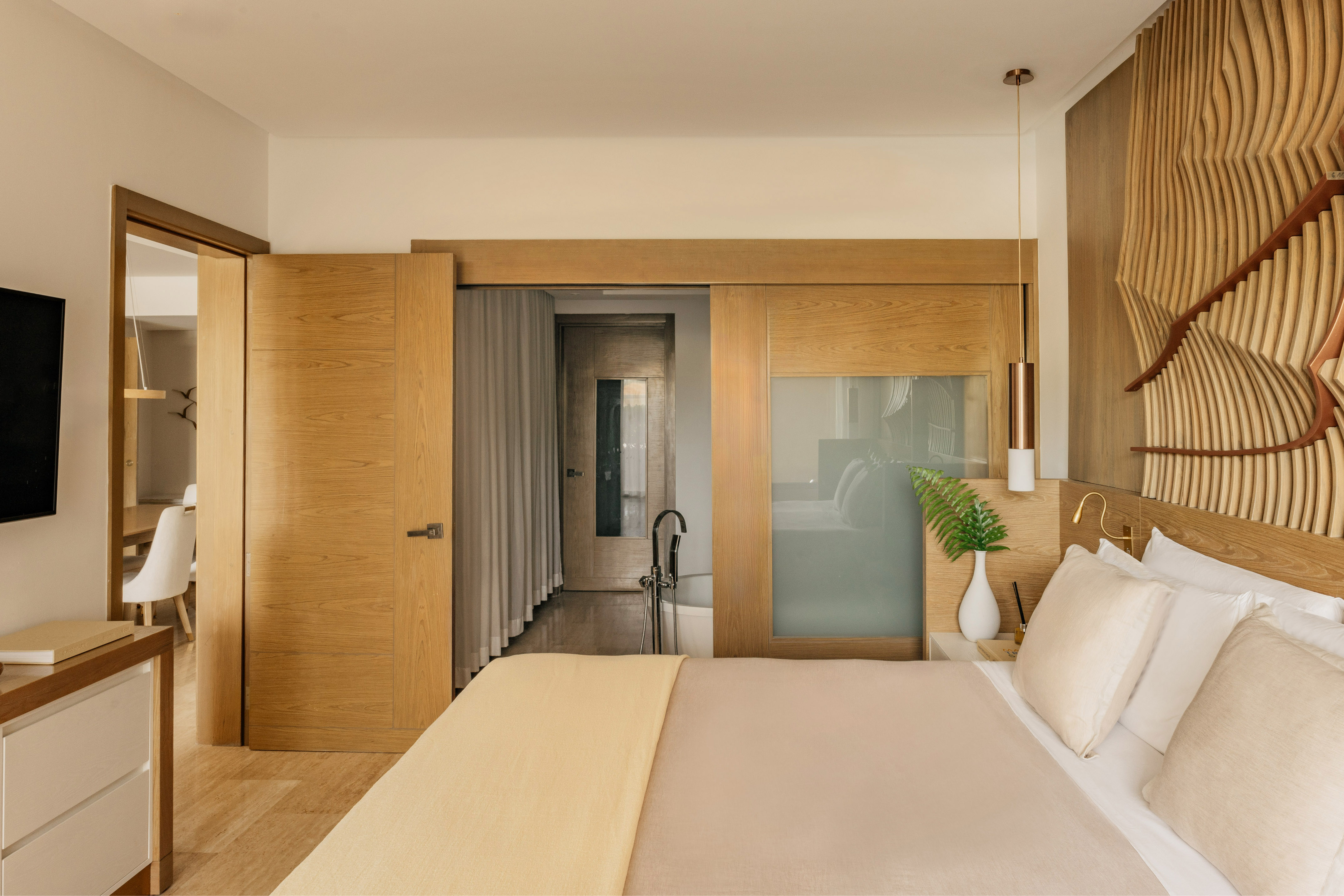 Modern bedroom with wooden headboard, sliding doors, and en-suite bathroom.