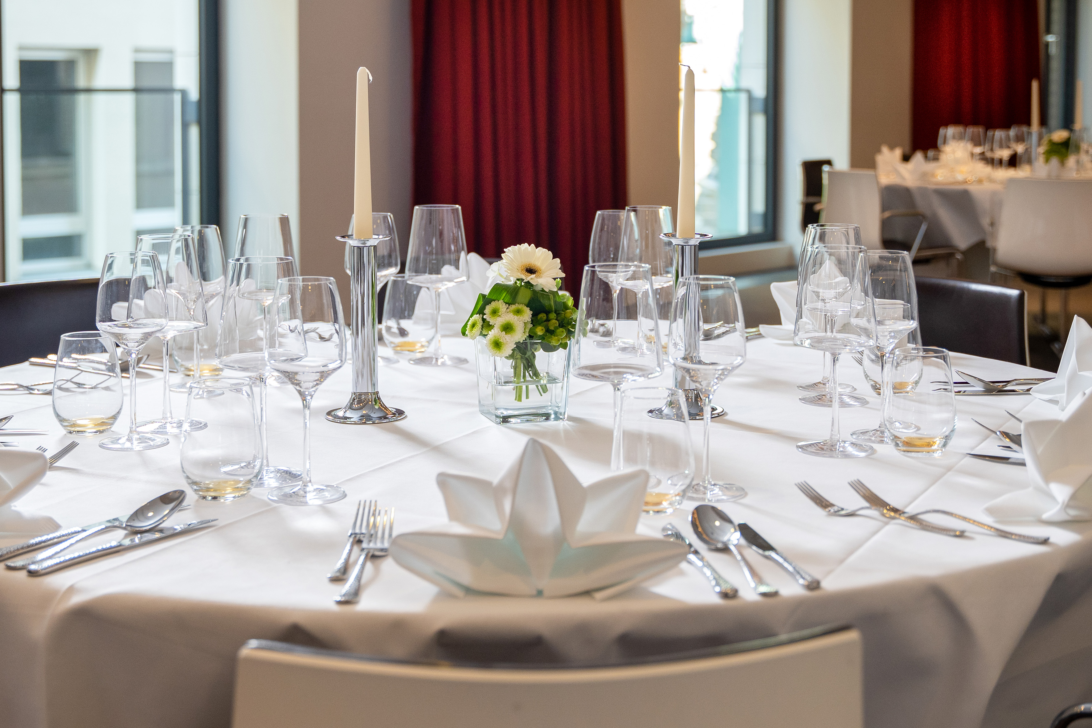 Formal dining table set with white linen, glasses, candles, and flowers. - CONEins + Zwei + Drei - Innside Dresda, Dresda