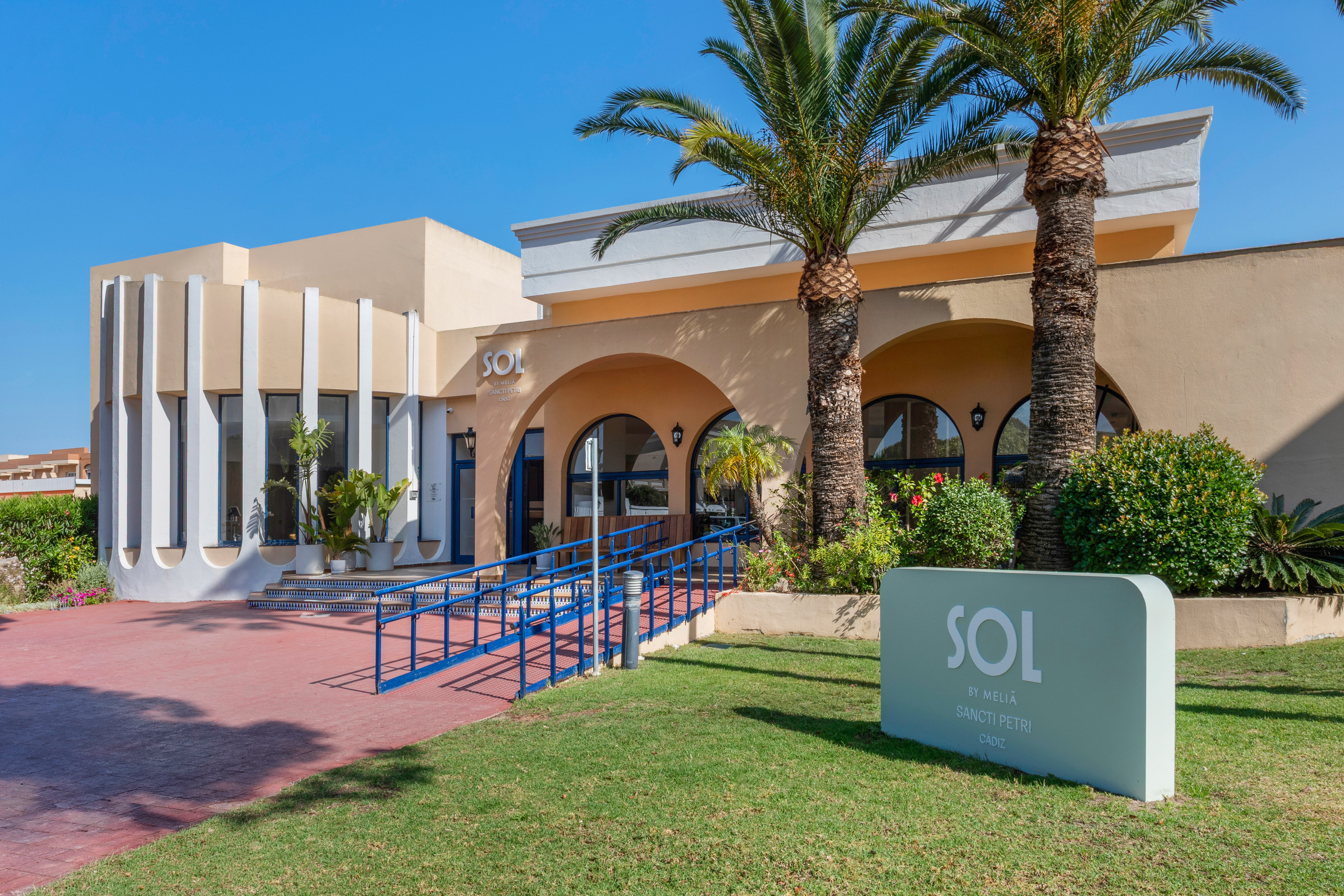 Sol by Meliã Sancti Petri hotel entrance, palm trees, and blue accessibility ramp.