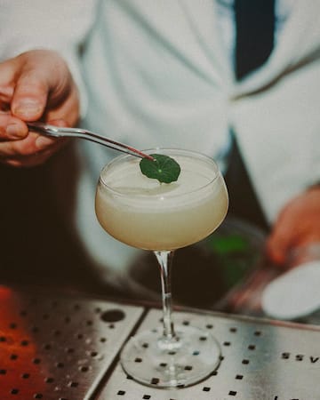 a person holding a tweezers over a glass of liquid