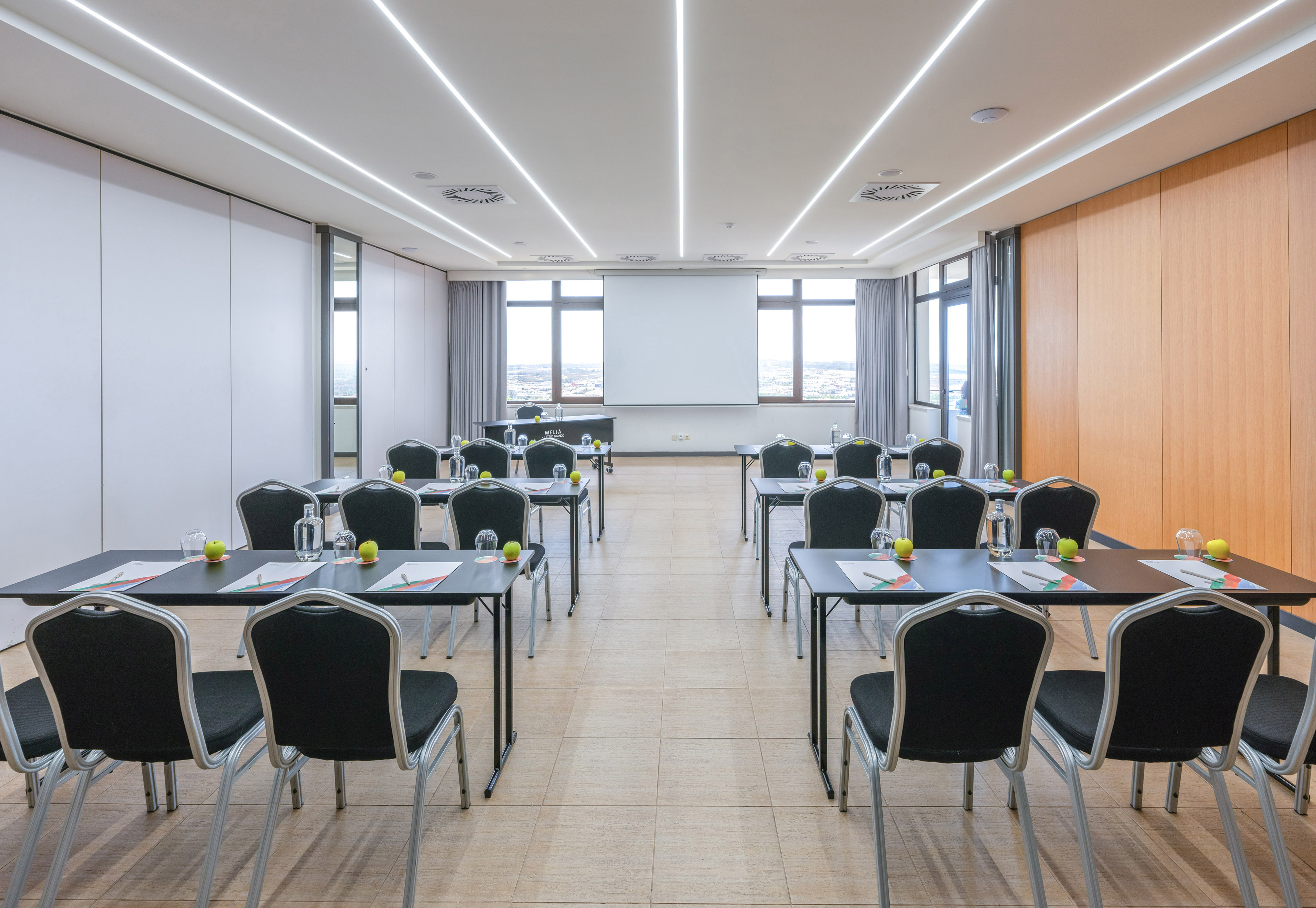 Modern conference room with projector screen, organized tables, and sleek lighting.