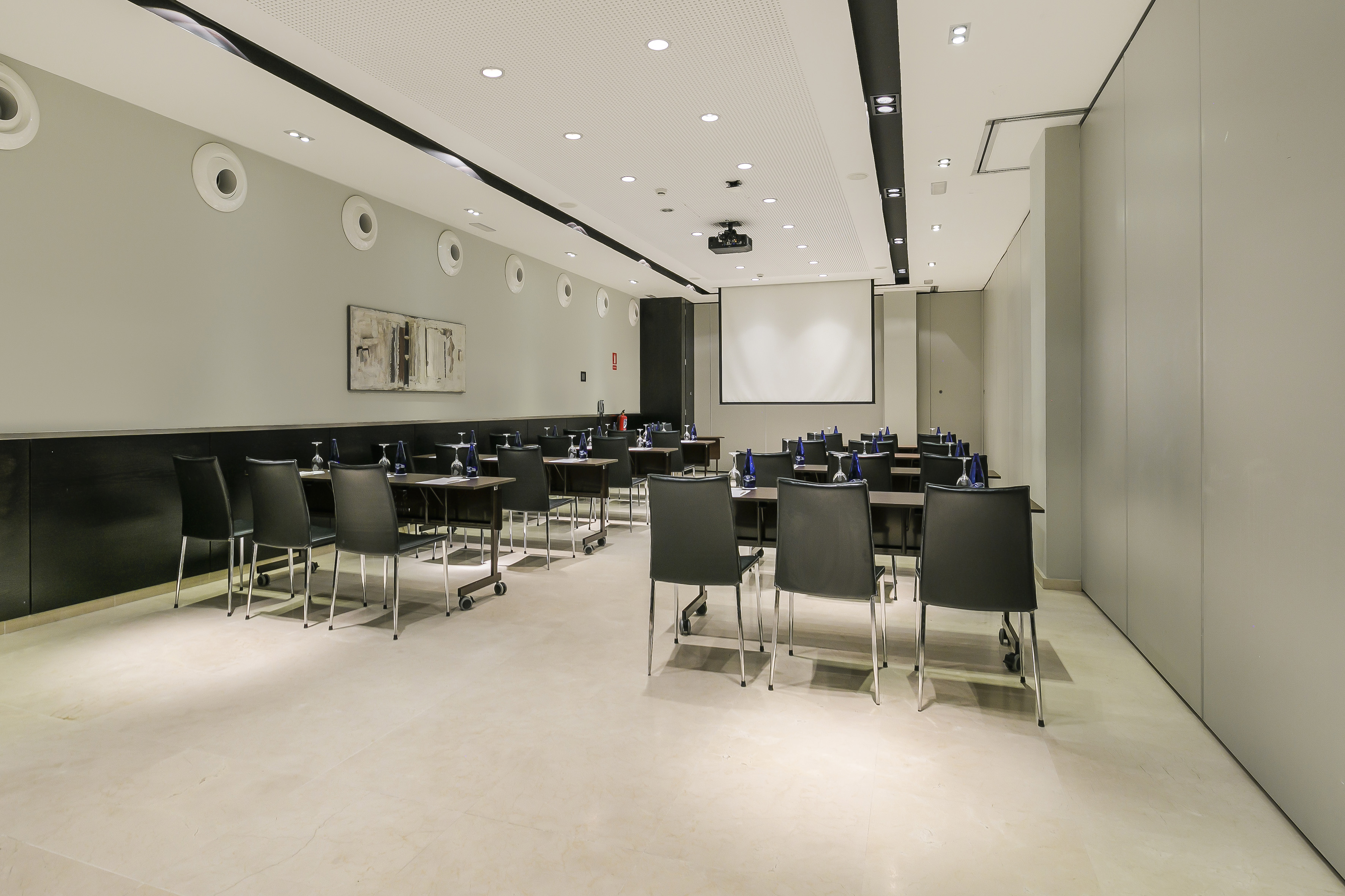 Modern conference room with tables, chairs, projector screen. Ready for meetings.