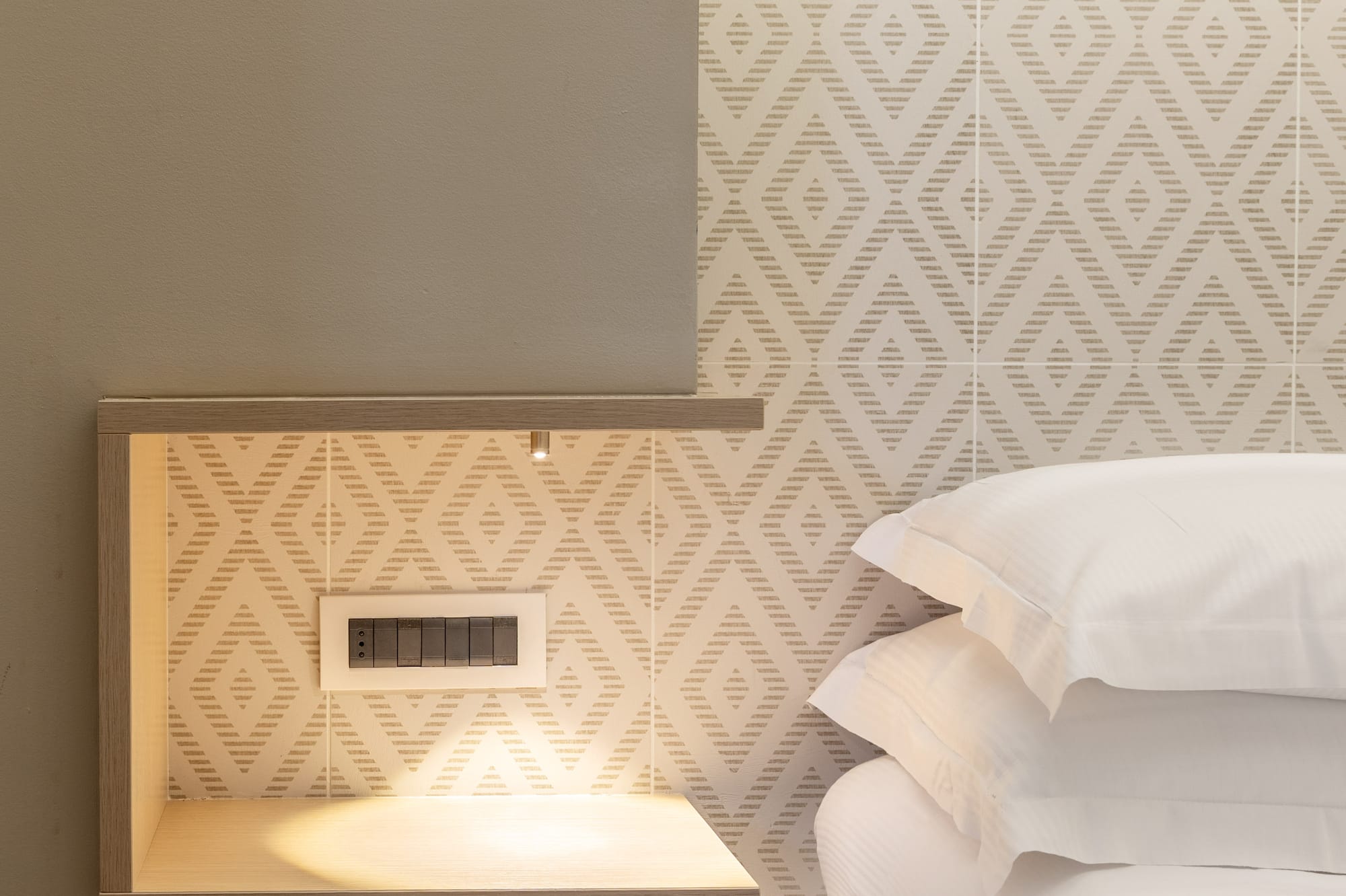 a bed with white pillows and a shelf in a room