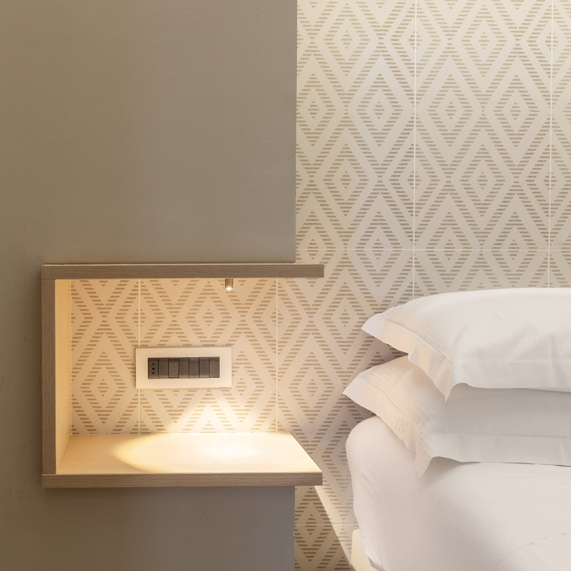 a bed with white pillows and a shelf in a room