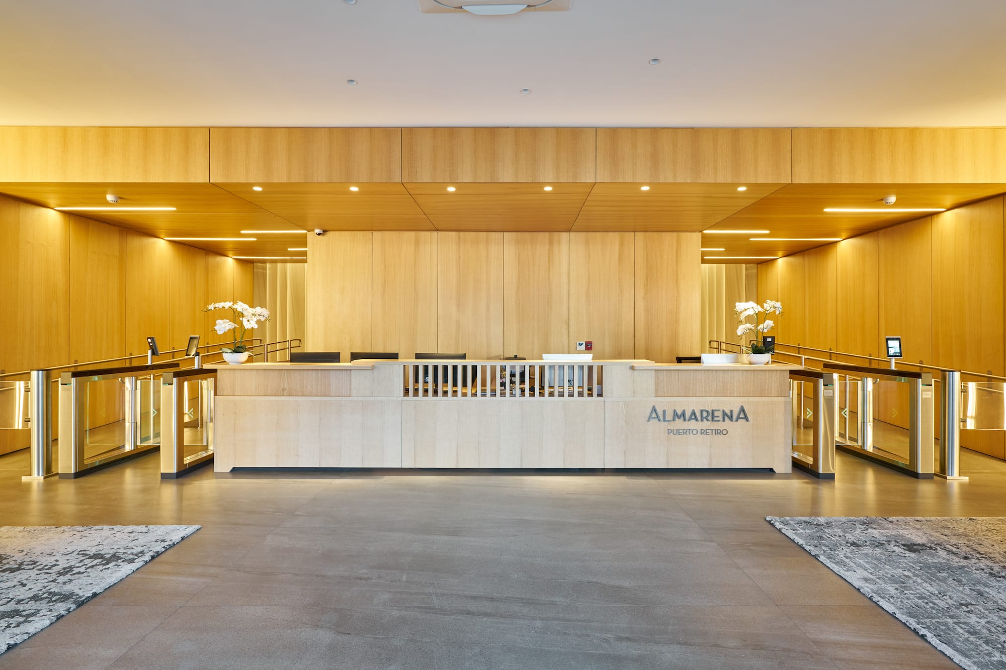Modern wooden office reception with Almarena Puerto Retiro sign and turnstiles.