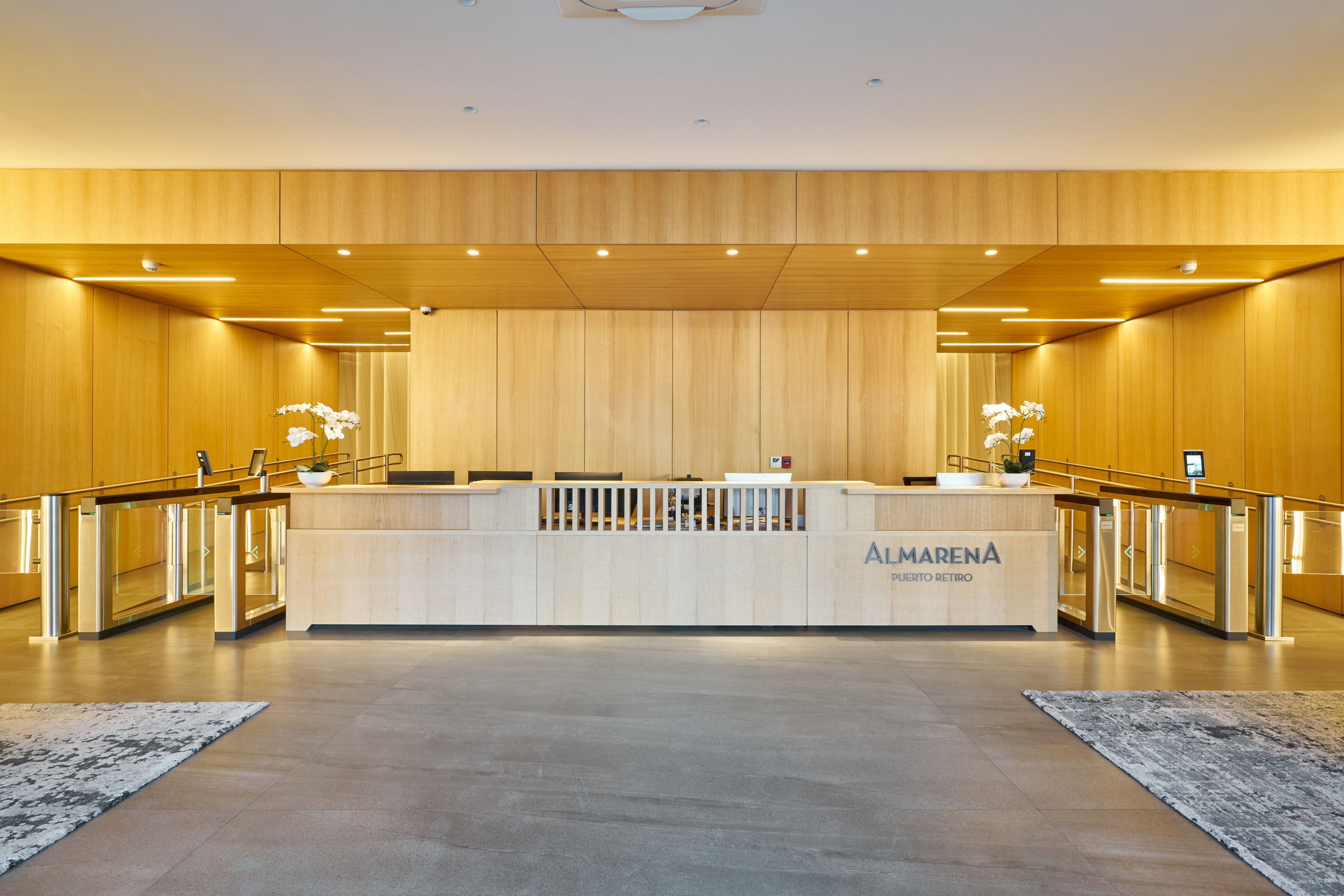 Modern wooden office reception with Almarena Puerto Retiro sign and turnstiles.