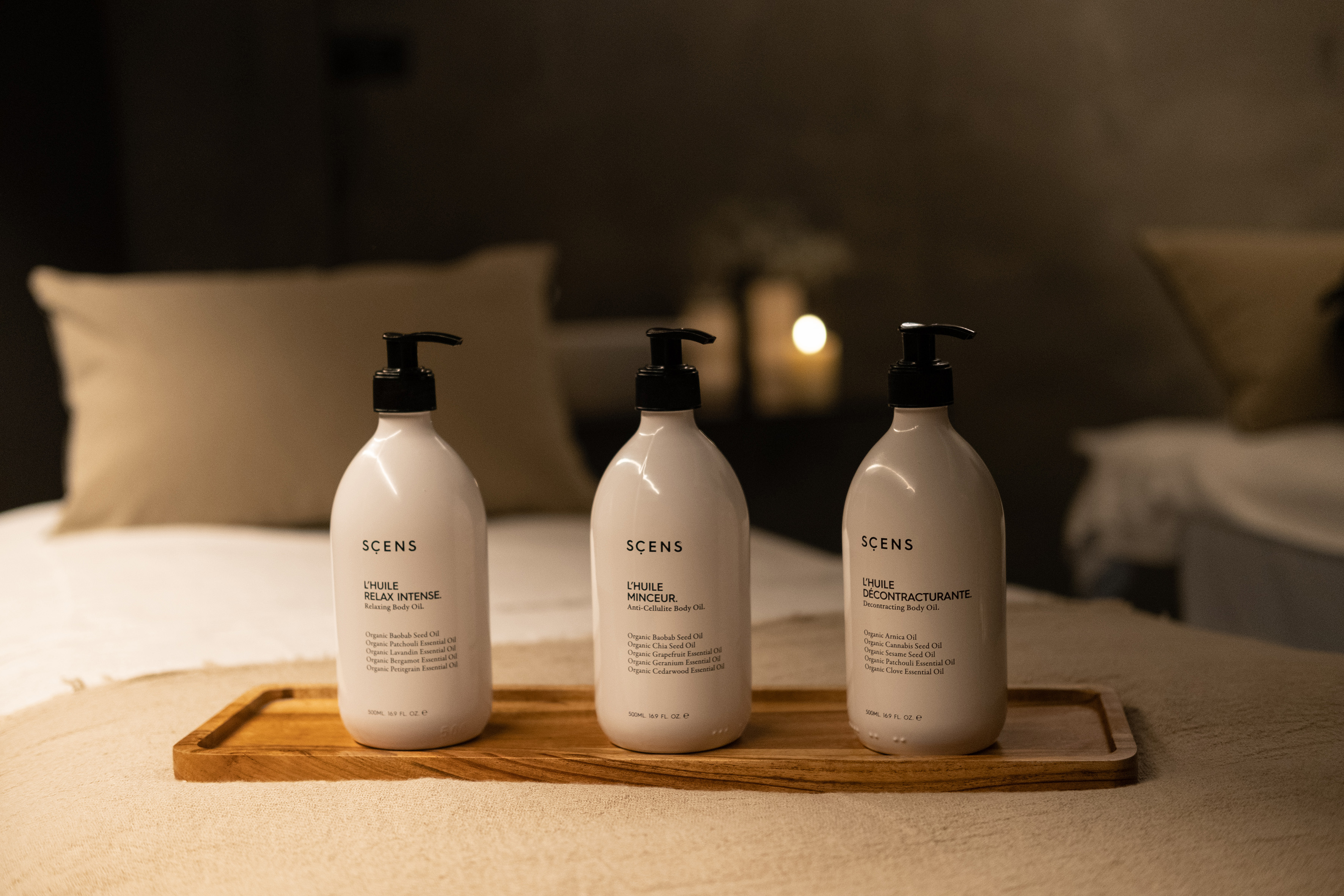 Three SCENS relaxing, anti-cellulite, decontracting body oils on a wooden tray.