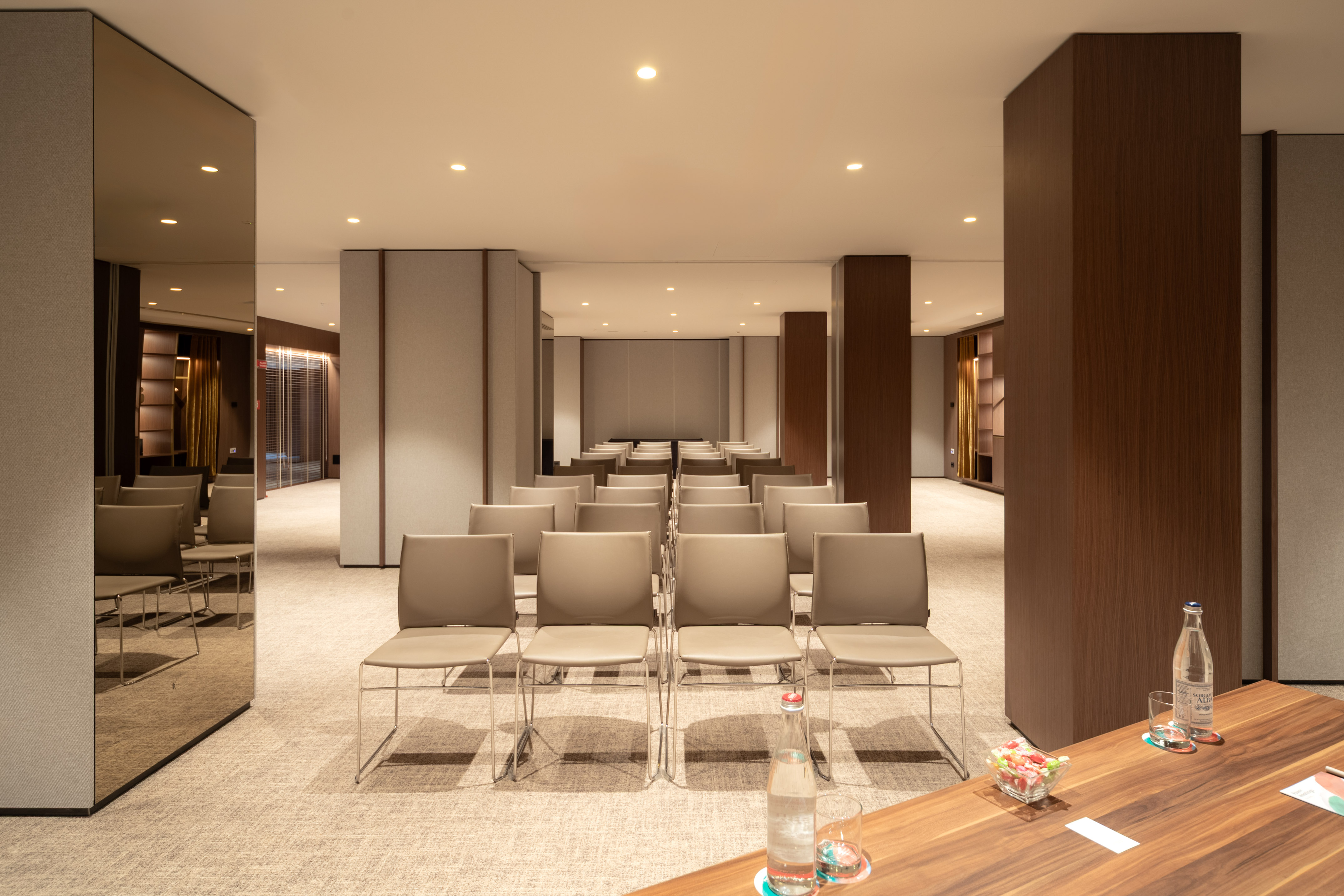 Modern conference room with rows of empty chairs, warm lighting, wood accents.