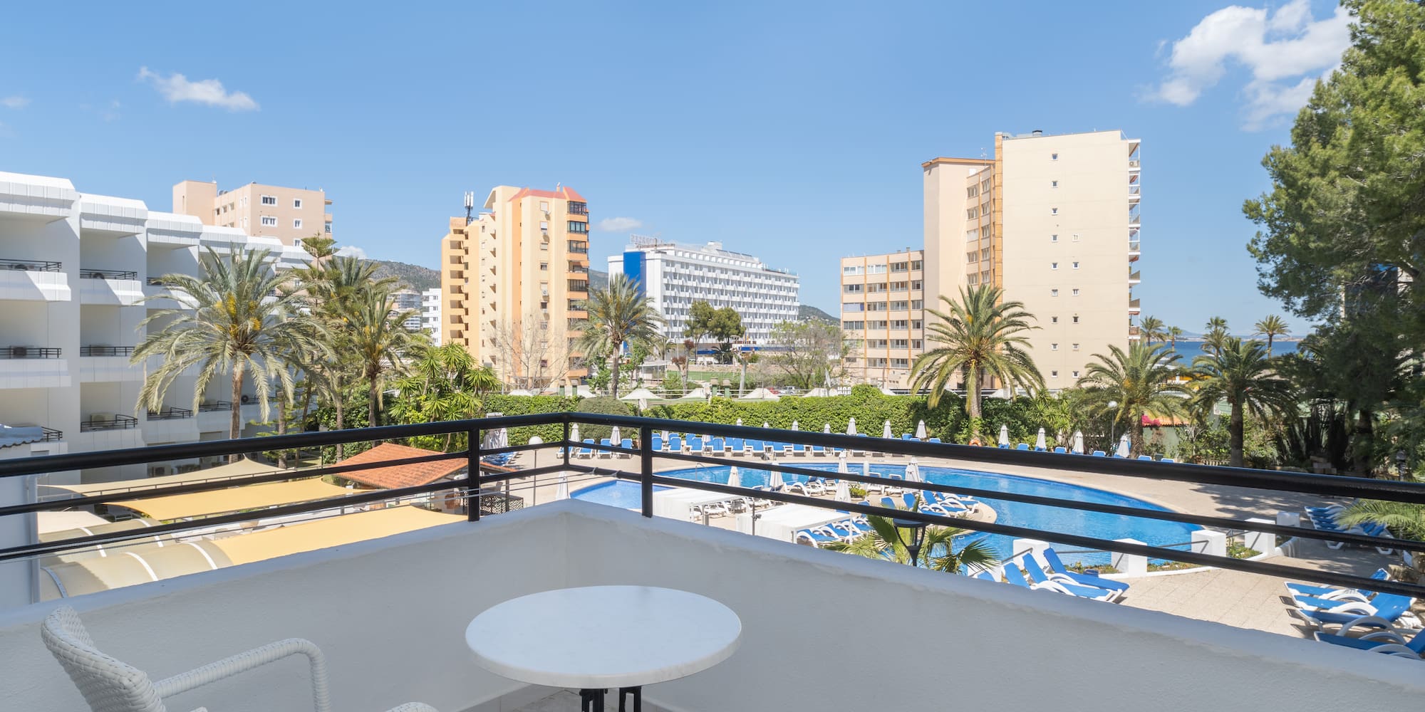 a balcony with a table and chairs and a pool in the background