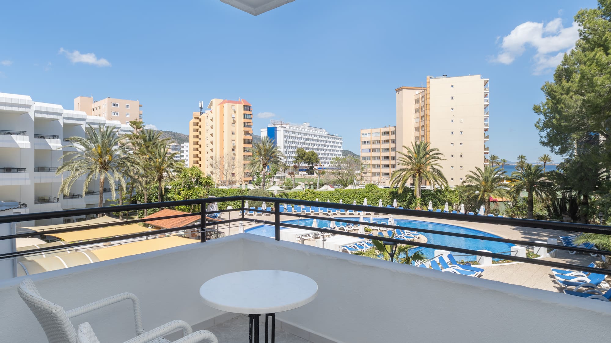 a balcony with a table and chairs and a pool in the background