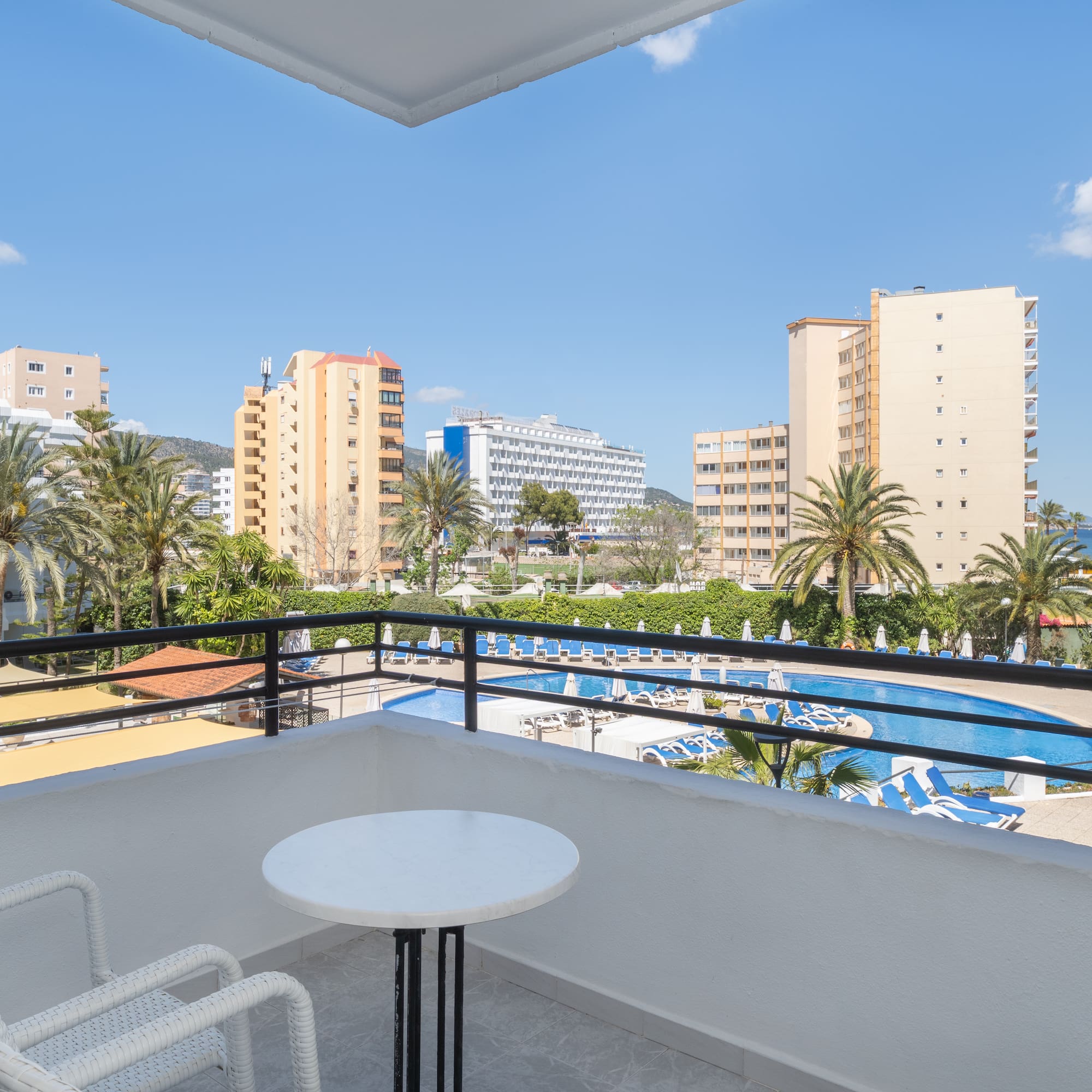 a balcony with a table and chairs and a pool in the background