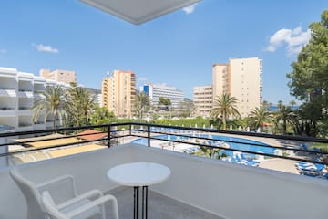 a balcony with a table and chairs and a pool in the background
