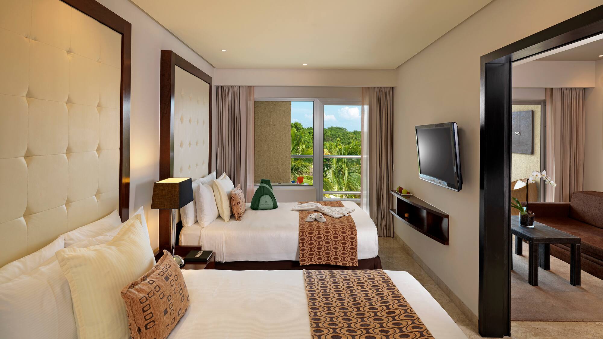 Hotel room with two queen beds, tropical view, TV, and separate living area.