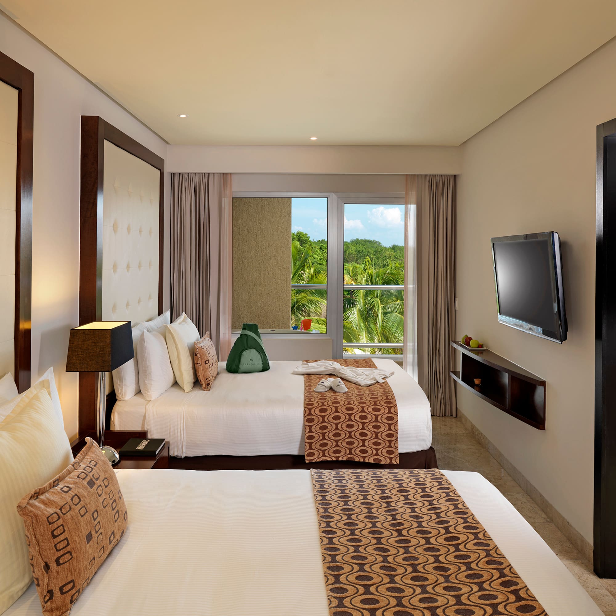 Hotel room with two queen beds, tropical view, TV, and separate living area.