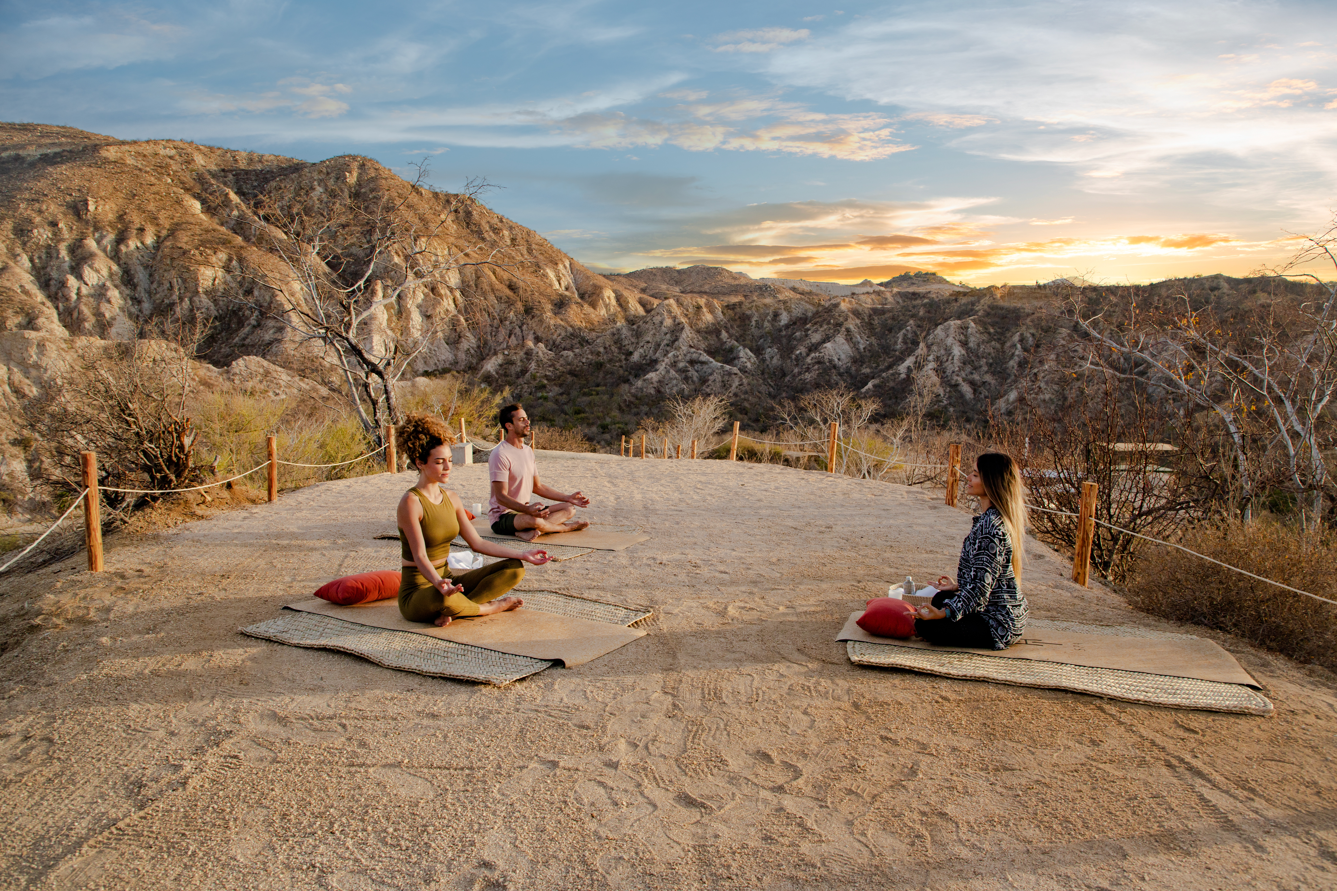 a group of people sitting on mats in a desert