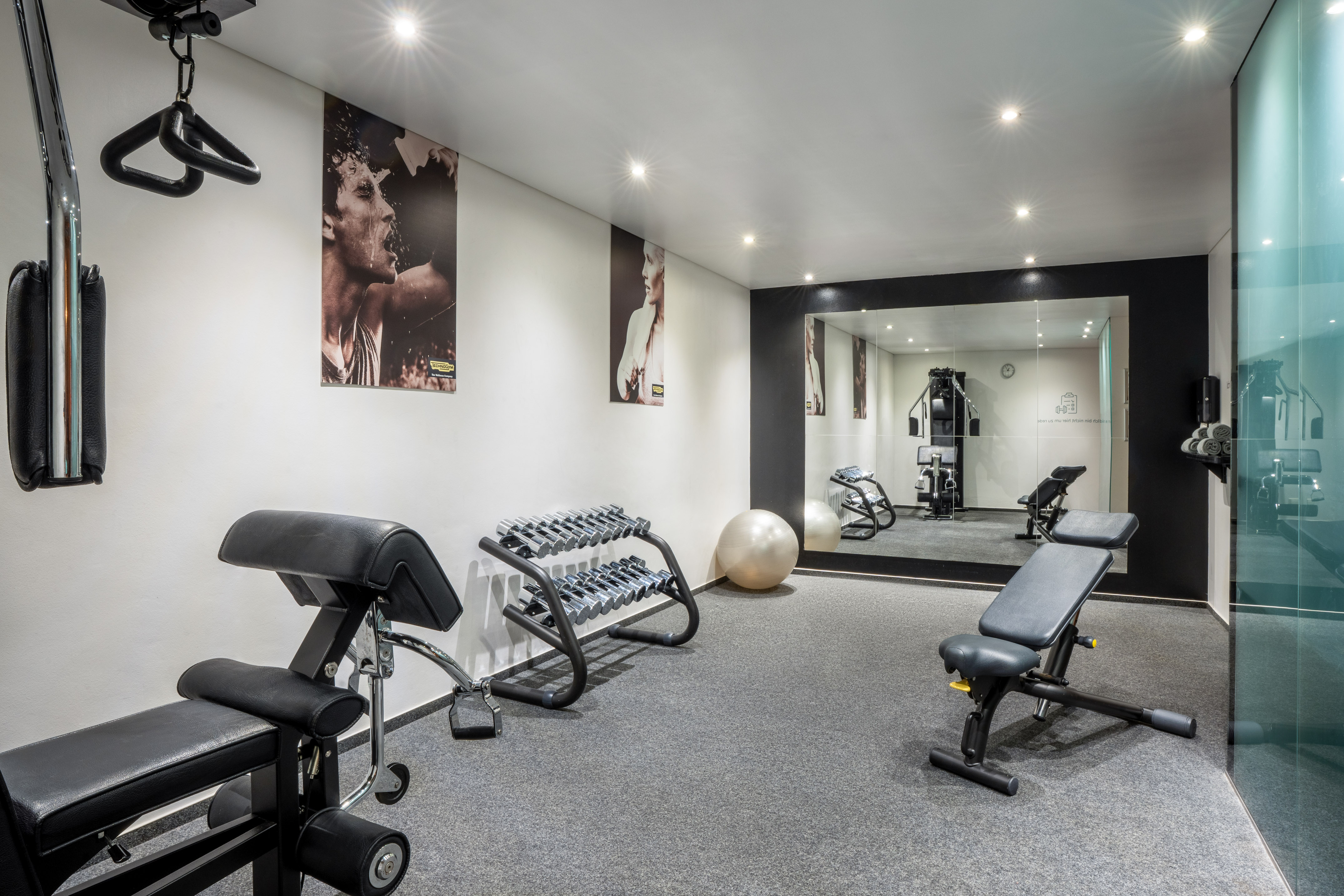 Modern gym with dumbbells, workout benches, and large mirror.