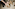 Poodle dog petted by hands, one with gold cuff bracelet, on terrazzo floor.