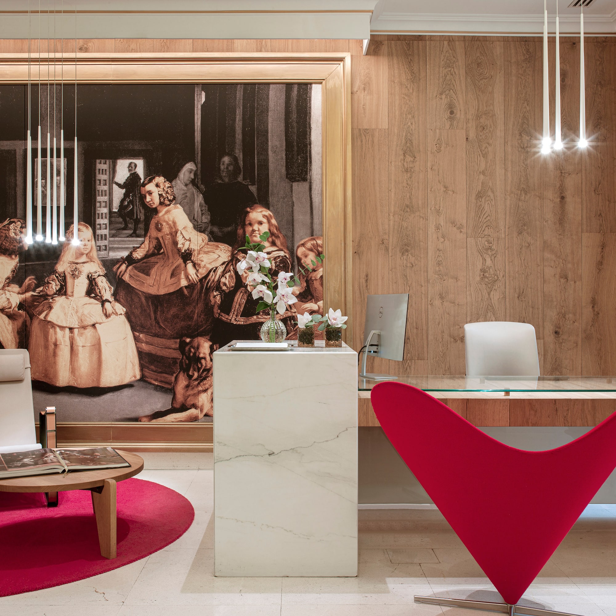 A desk sits in a room adorned with a large painting on the wall.