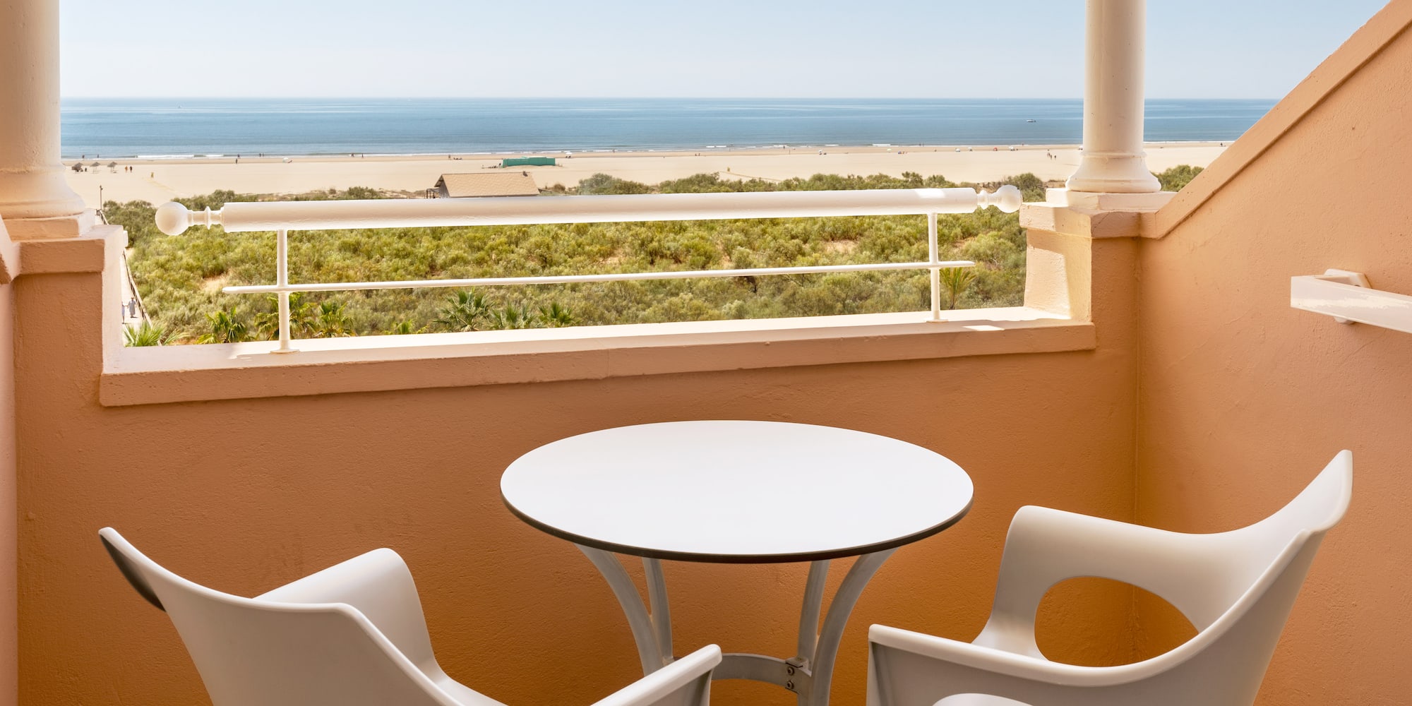 a table and chairs on a balcony overlooking a beach