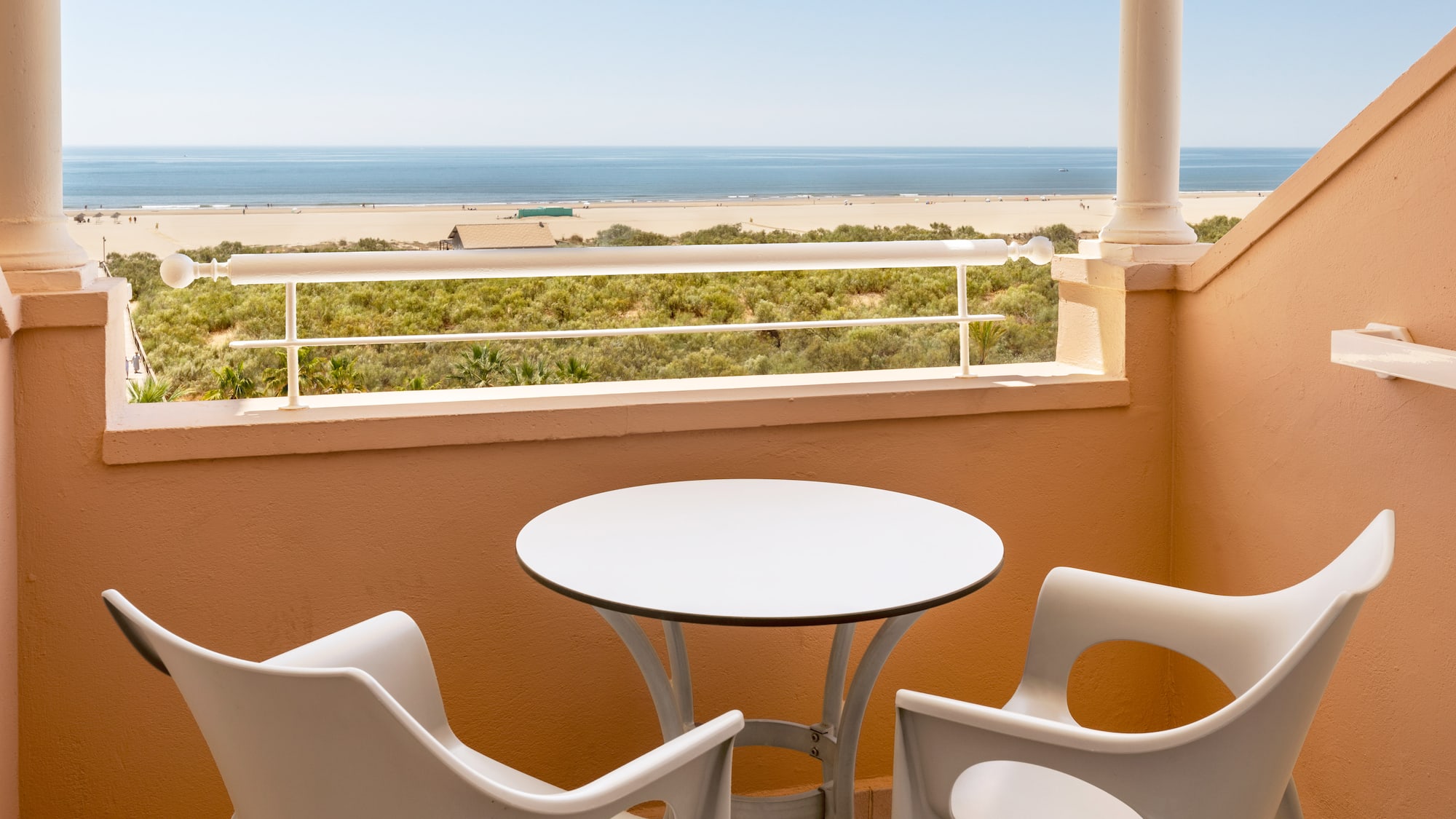 a table and chairs on a balcony overlooking a beach