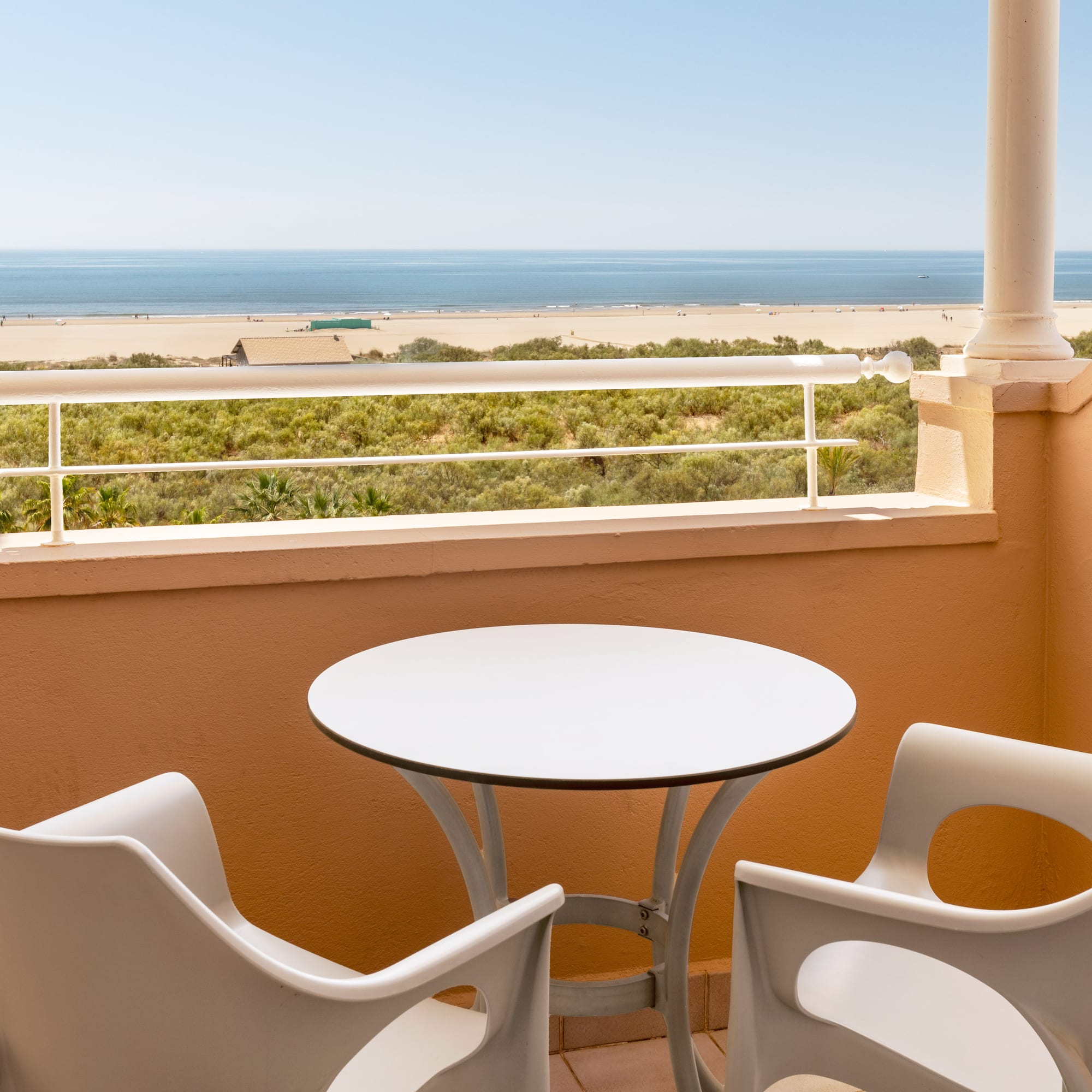 a table and chairs on a balcony overlooking a beach