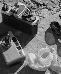 a camera and sunglasses on a rock