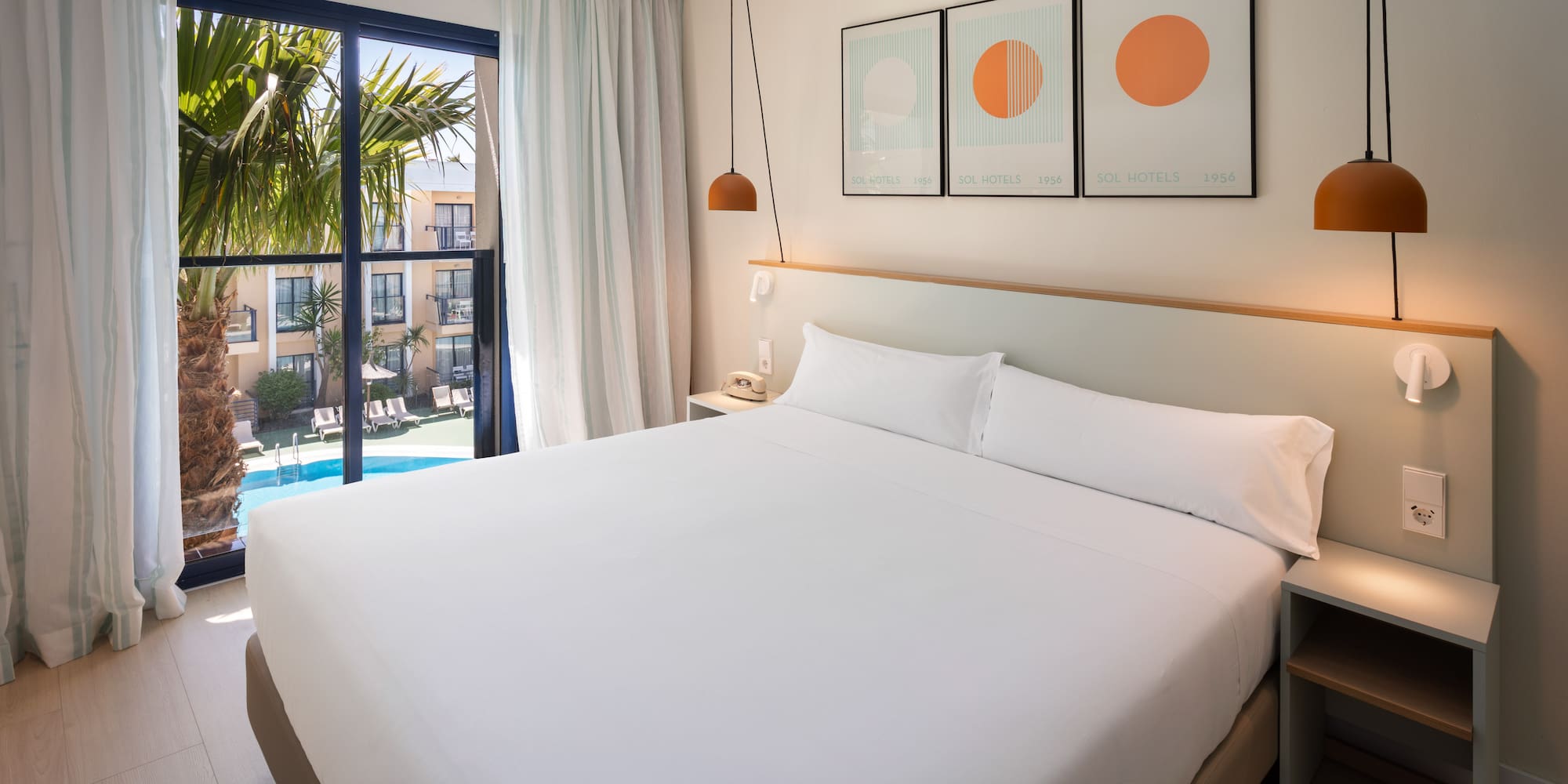 a bed with white sheets and pillows in a hotel room