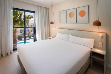 a bed with white sheets and pillows in a hotel room