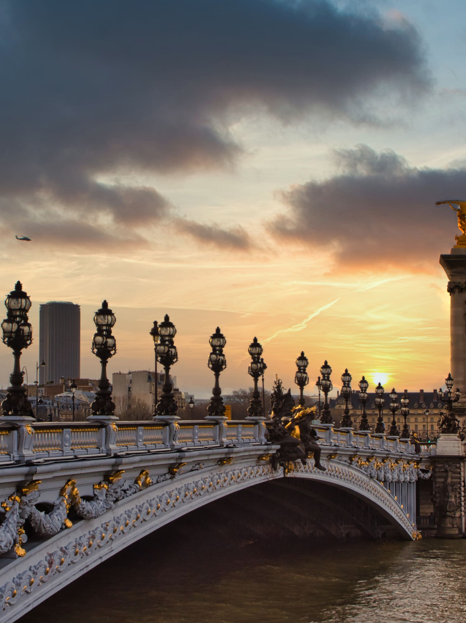 a bridge with a body of water and statues