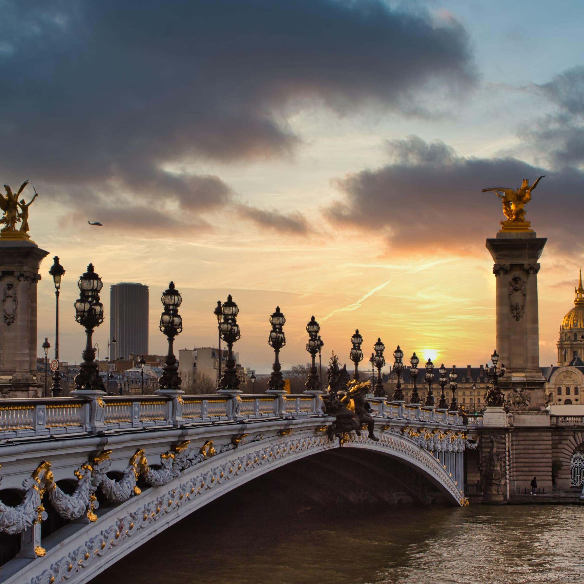 a bridge with a body of water and statues