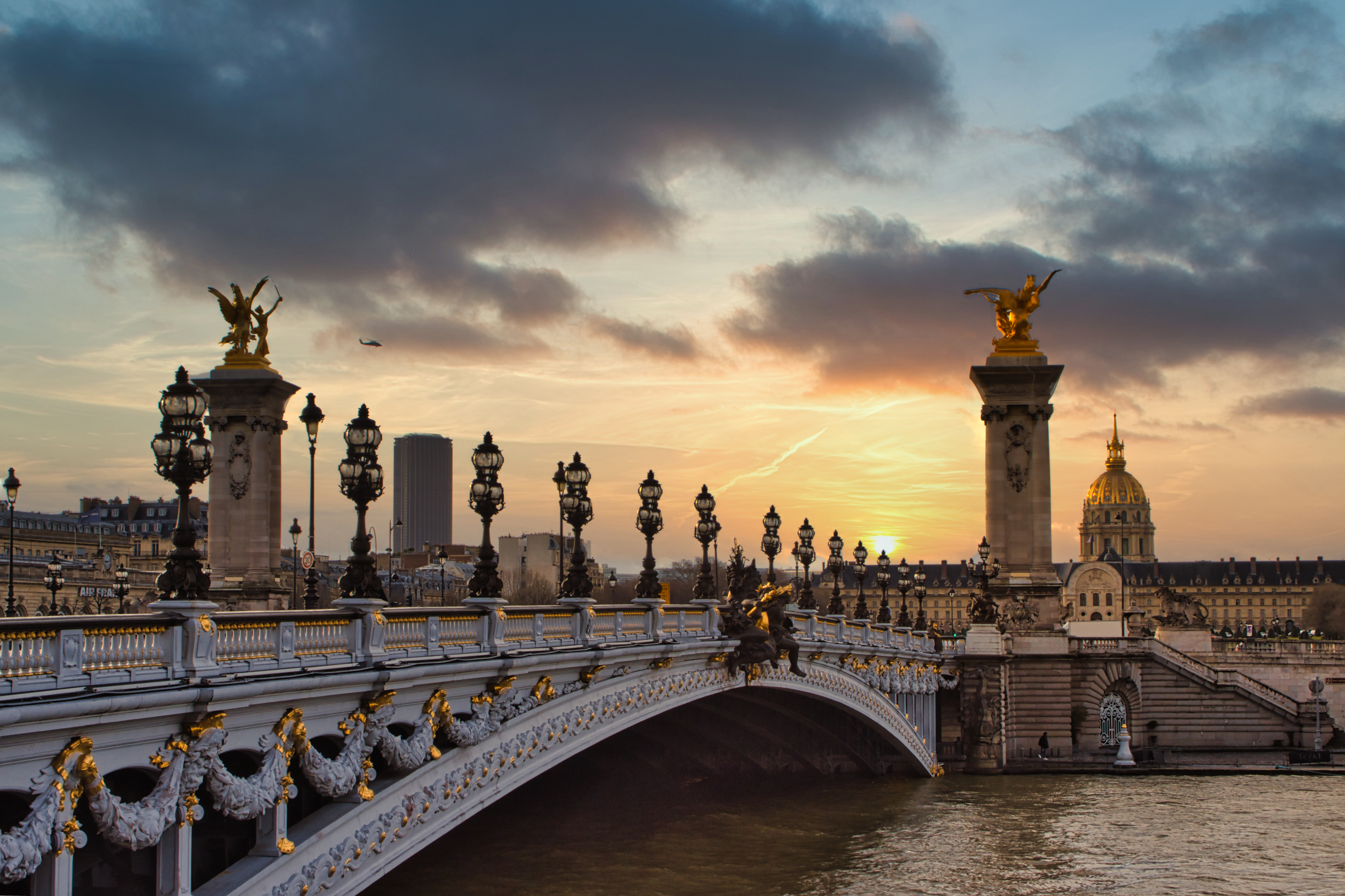 a bridge with a body of water and statues