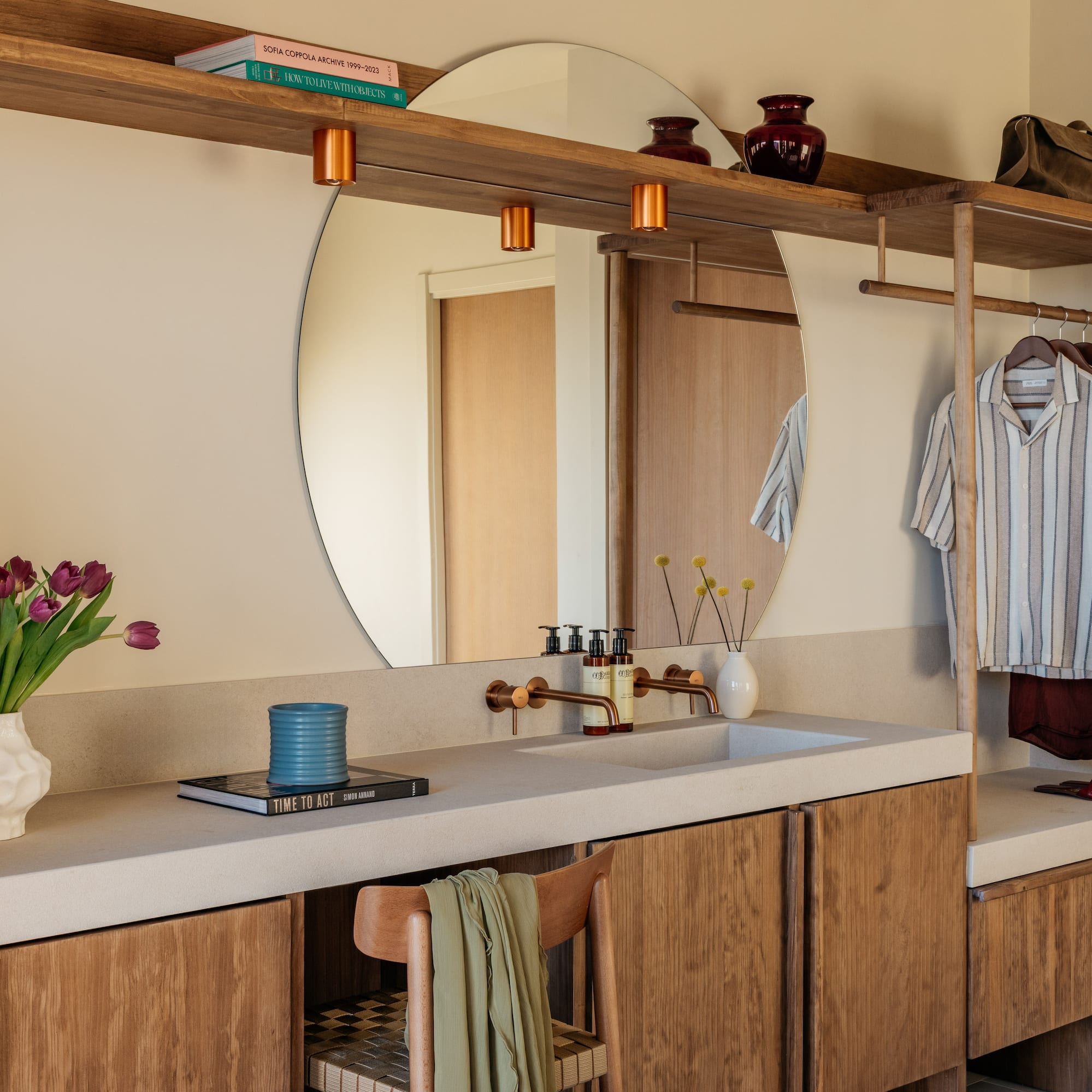 Modern bathroom vanity, round mirror, copper fixtures, and built-in storage.