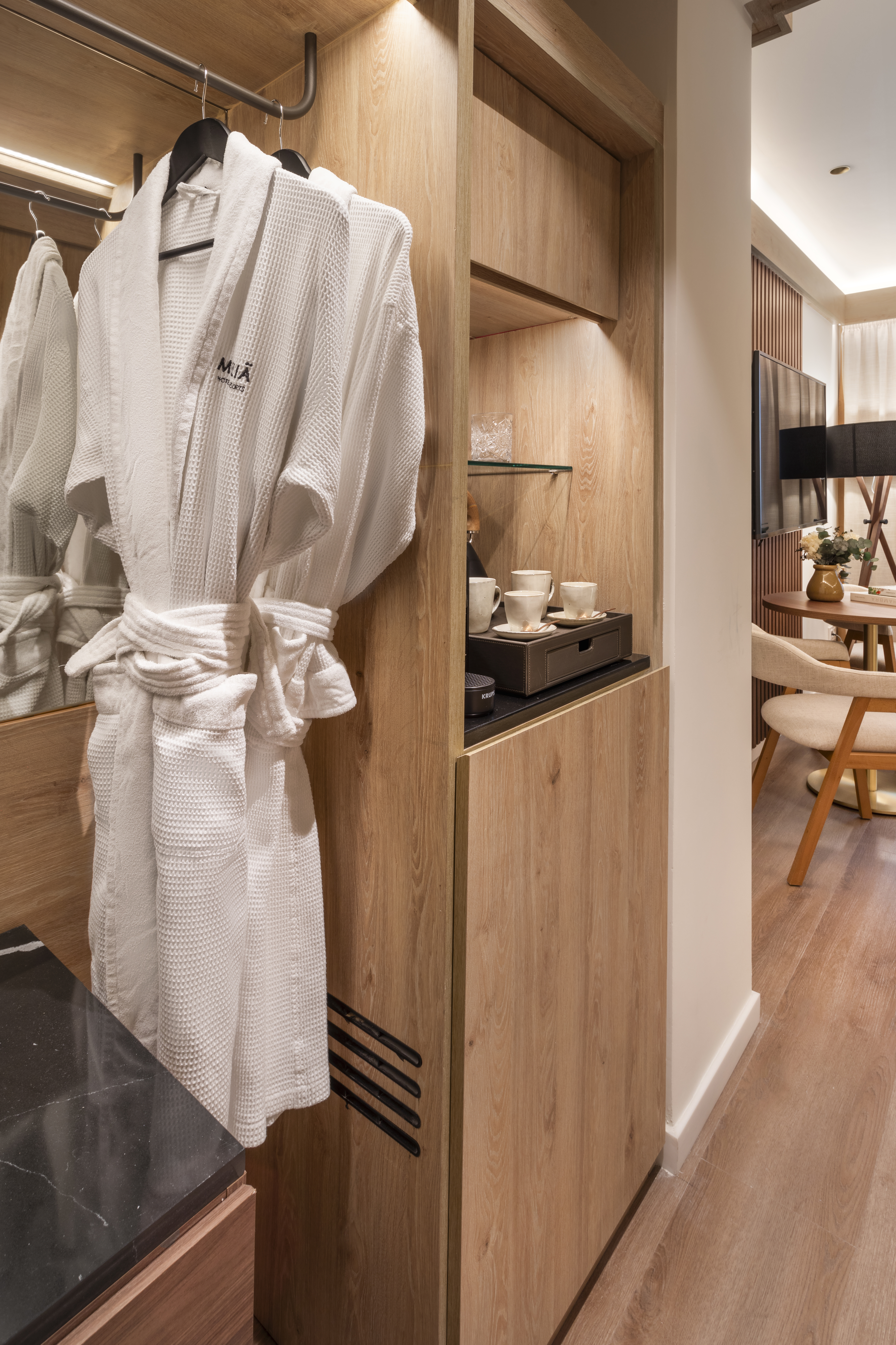 White waffle bathrobe in hotel wardrobe with coffee station and modern room amenities.