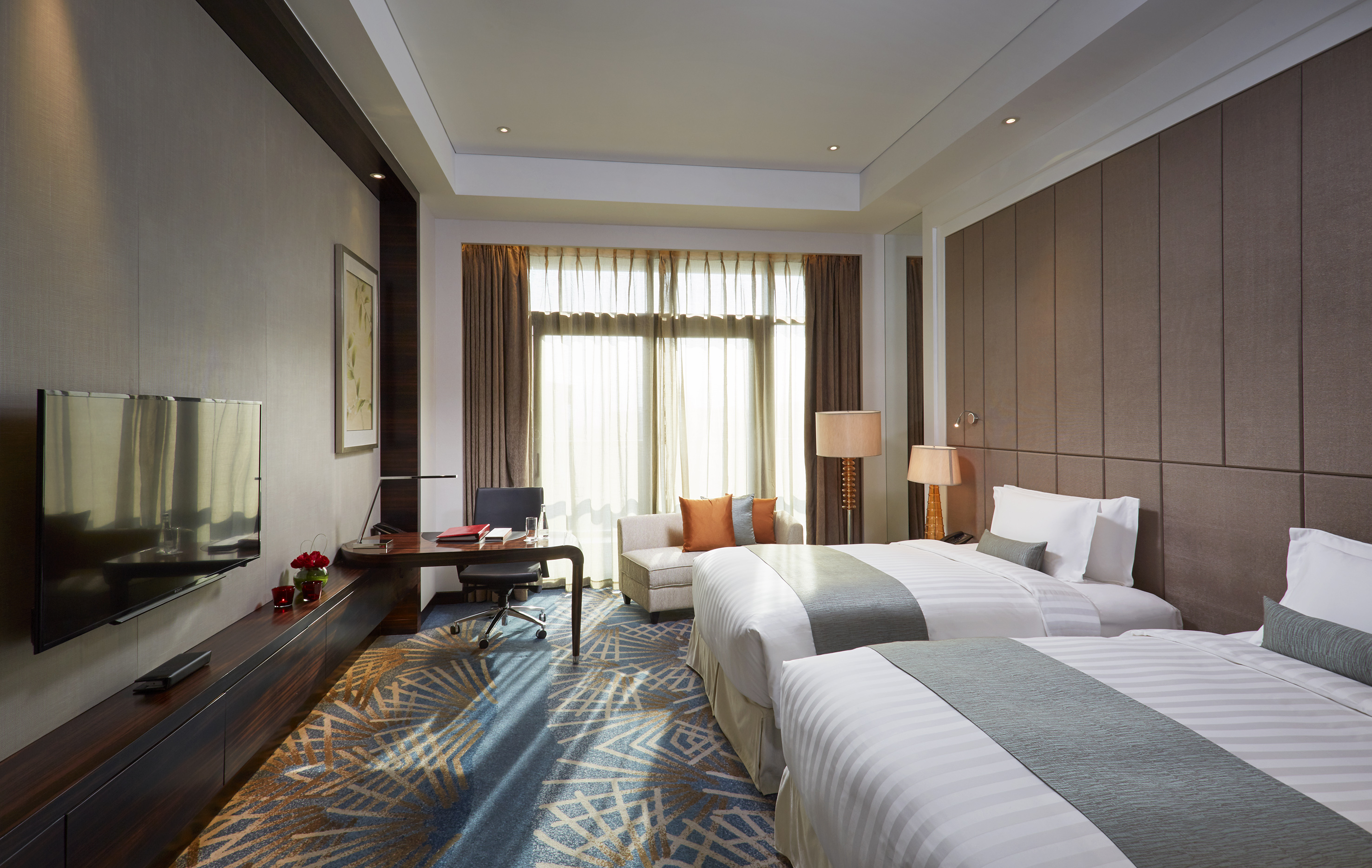 Luxury hotel twin room with workspace, TV, and contemporary decor.
