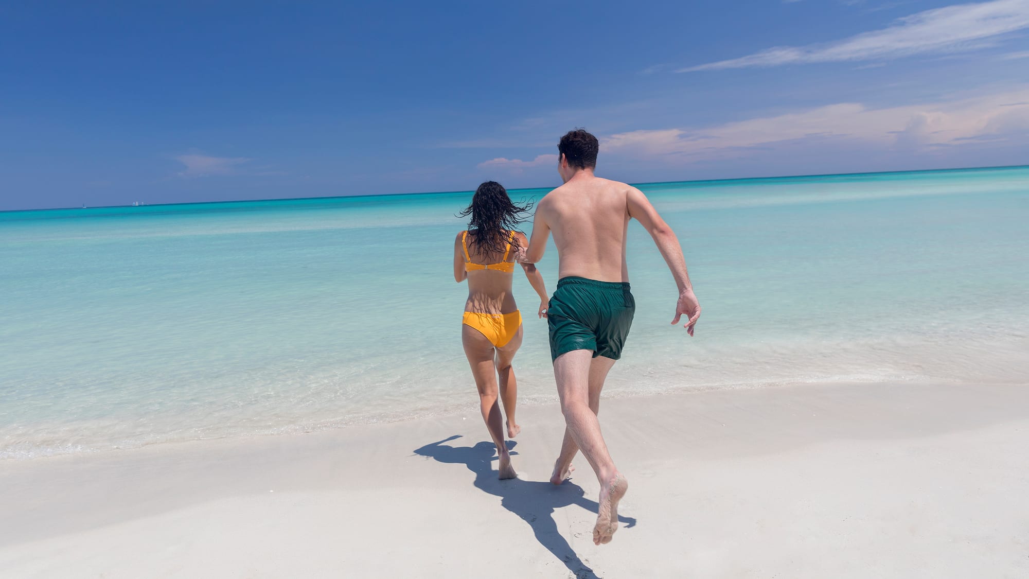 a man and woman running on a beach