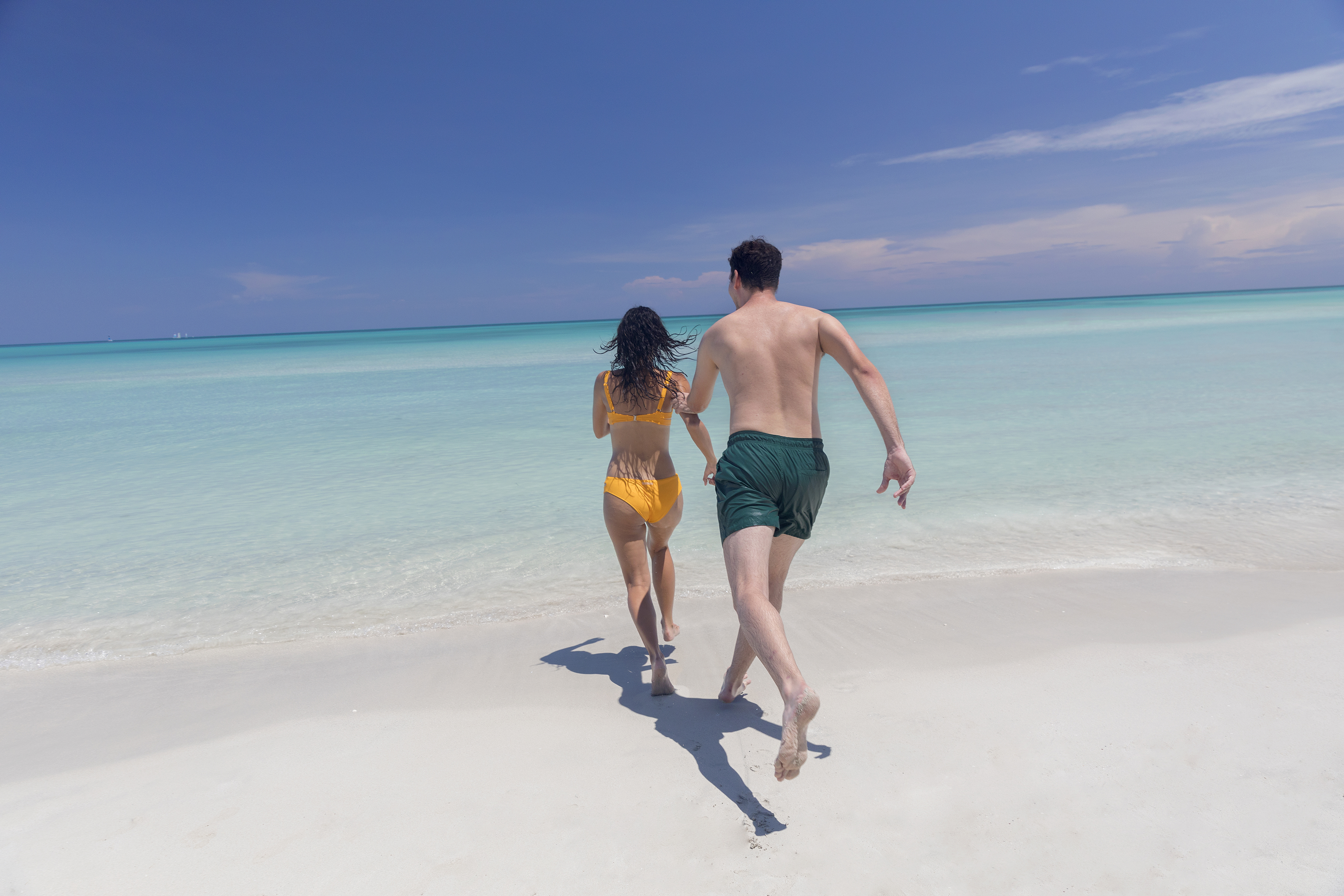 a man and woman running on a beach