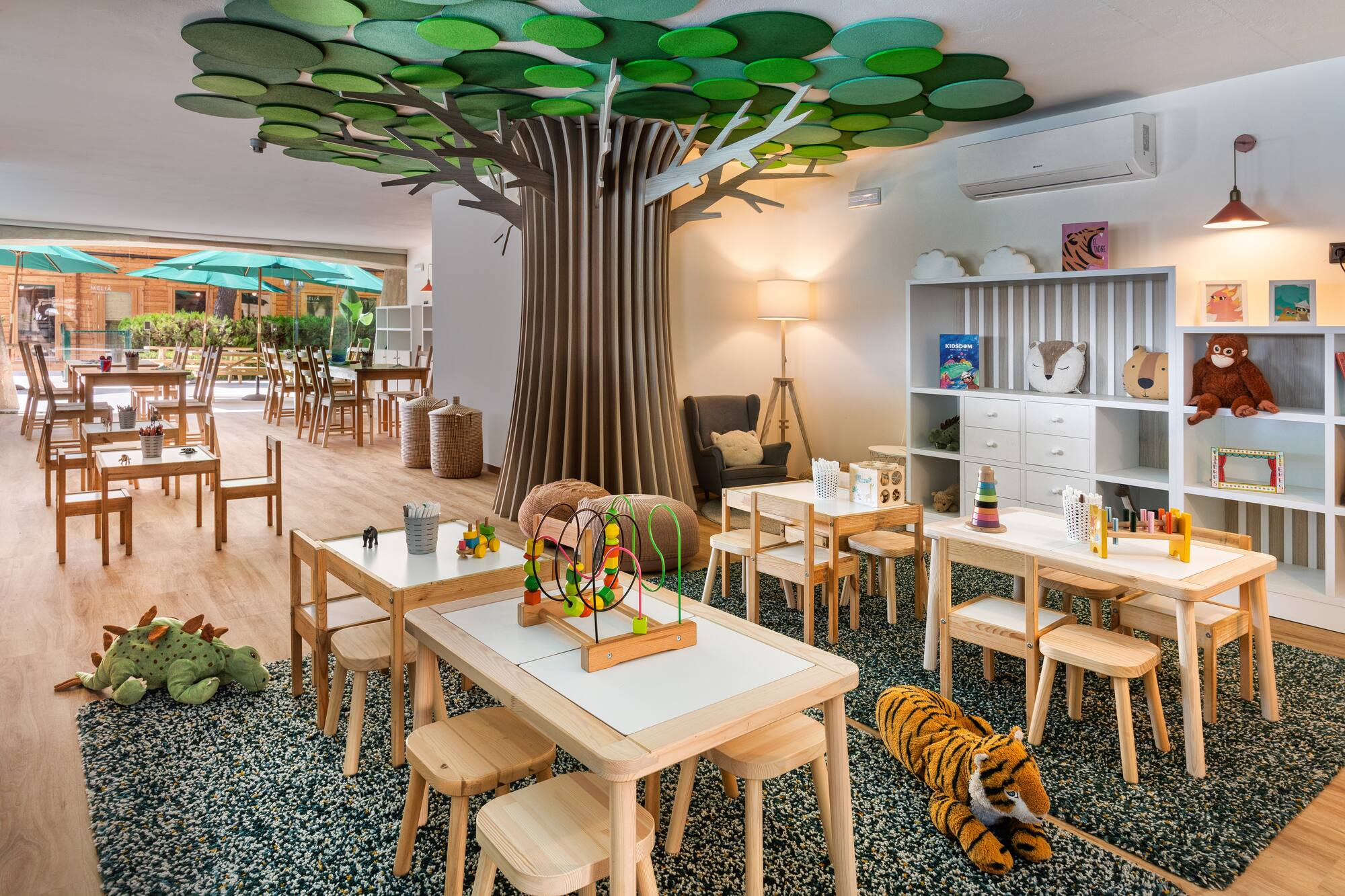 Vibrant children's club playroom featuring a tree, small tables, and engaging toys.