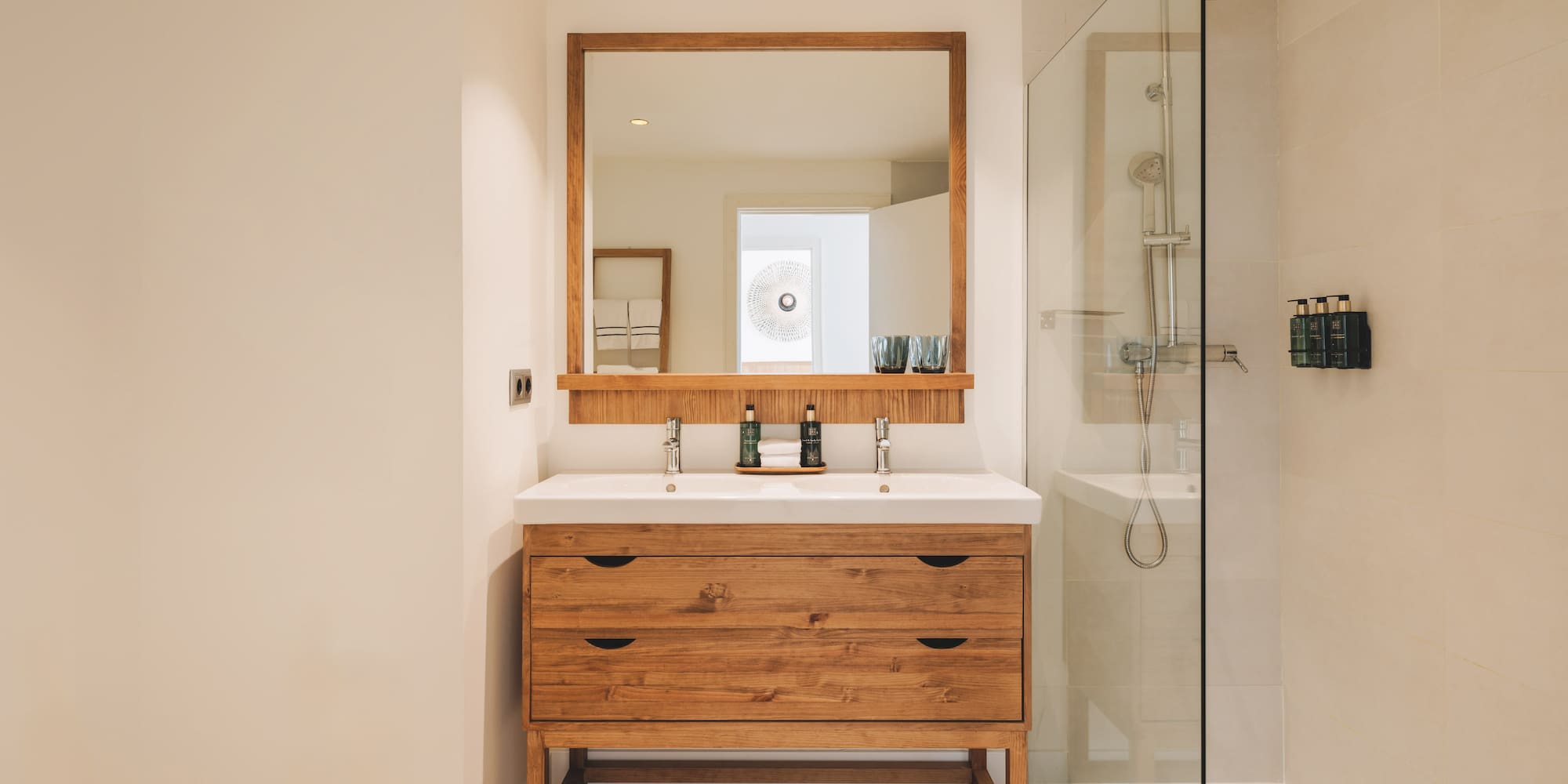 Modern bathroom with wood double vanity, double sink, mirror, and glass shower.