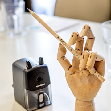 a wooden hand holding a pencil