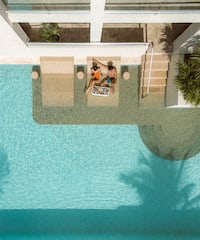 a man and woman sitting on a lounge chair next to a pool