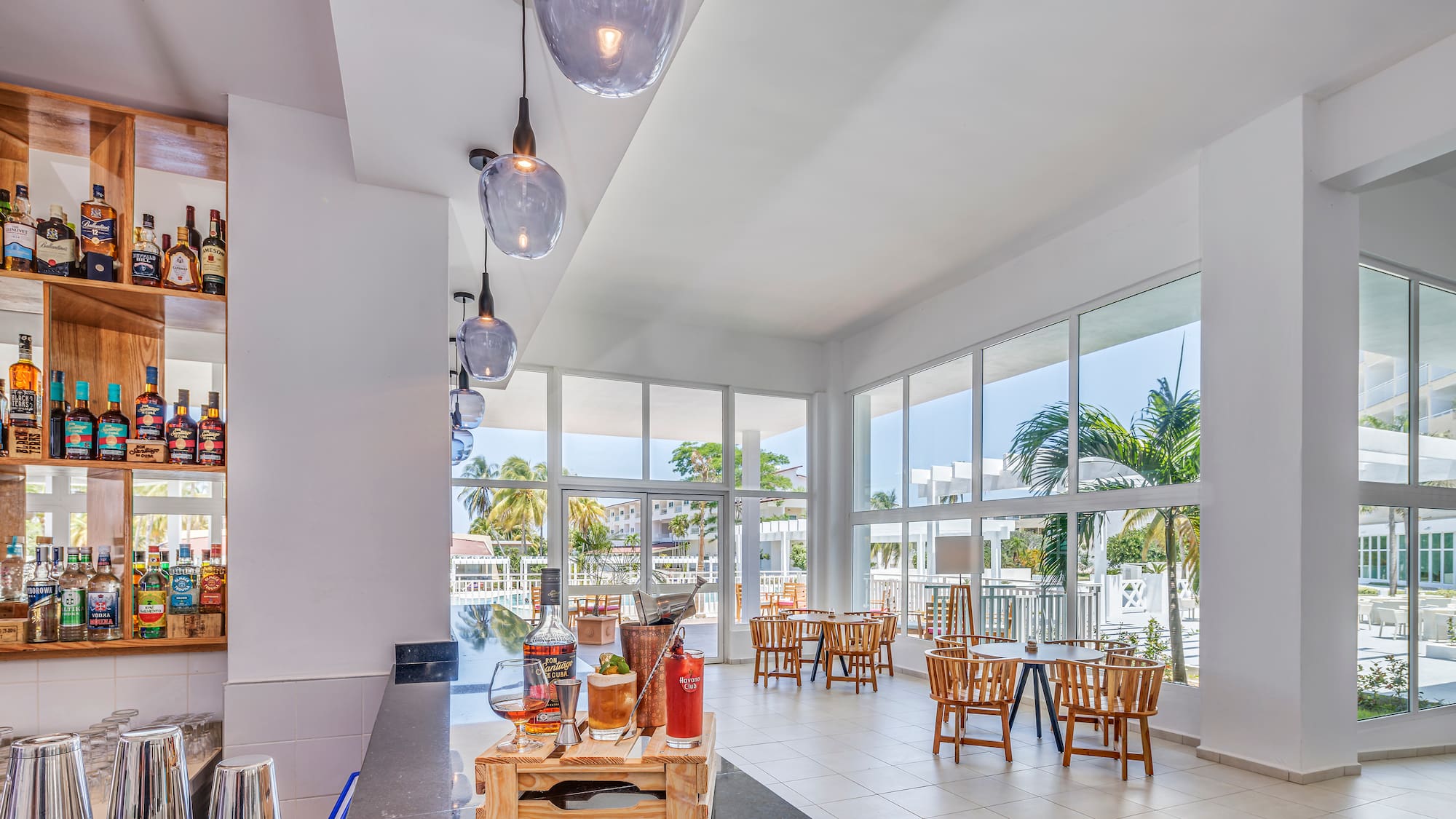 a room with tables and chairs and a table with a few windows