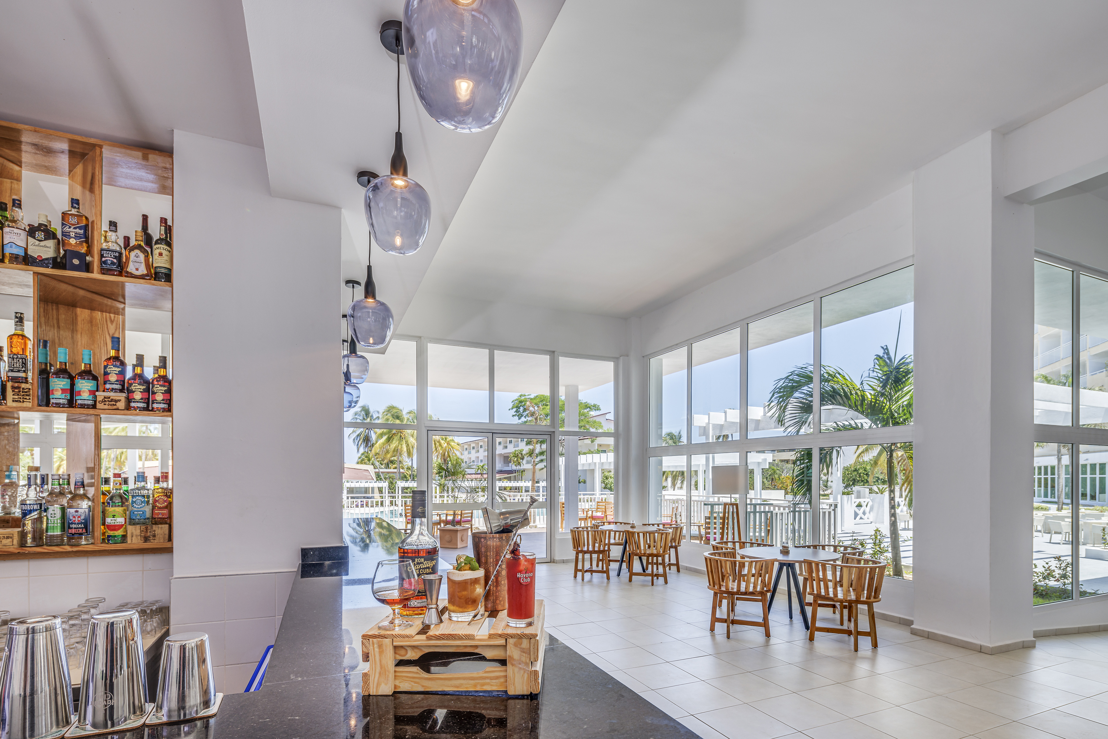 a room with tables and chairs and a table with a few windows