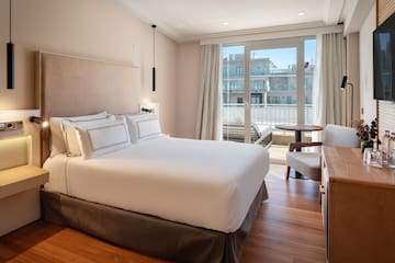a bed with a chair and a desk in a hotel room