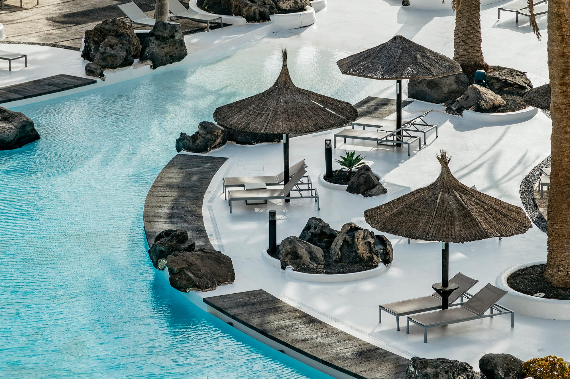 a pool with umbrellas and chairs and palm trees