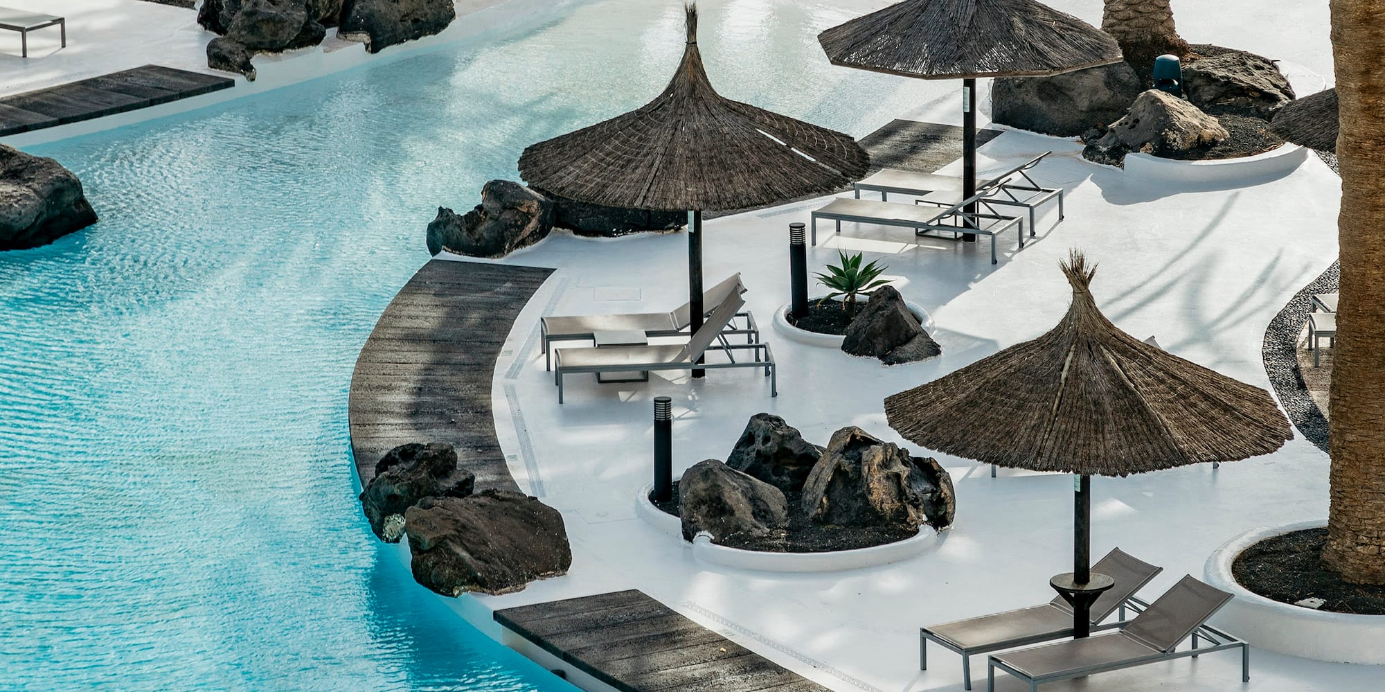 a pool with umbrellas and chairs and palm trees