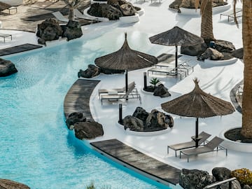 a pool with umbrellas and chairs and palm trees